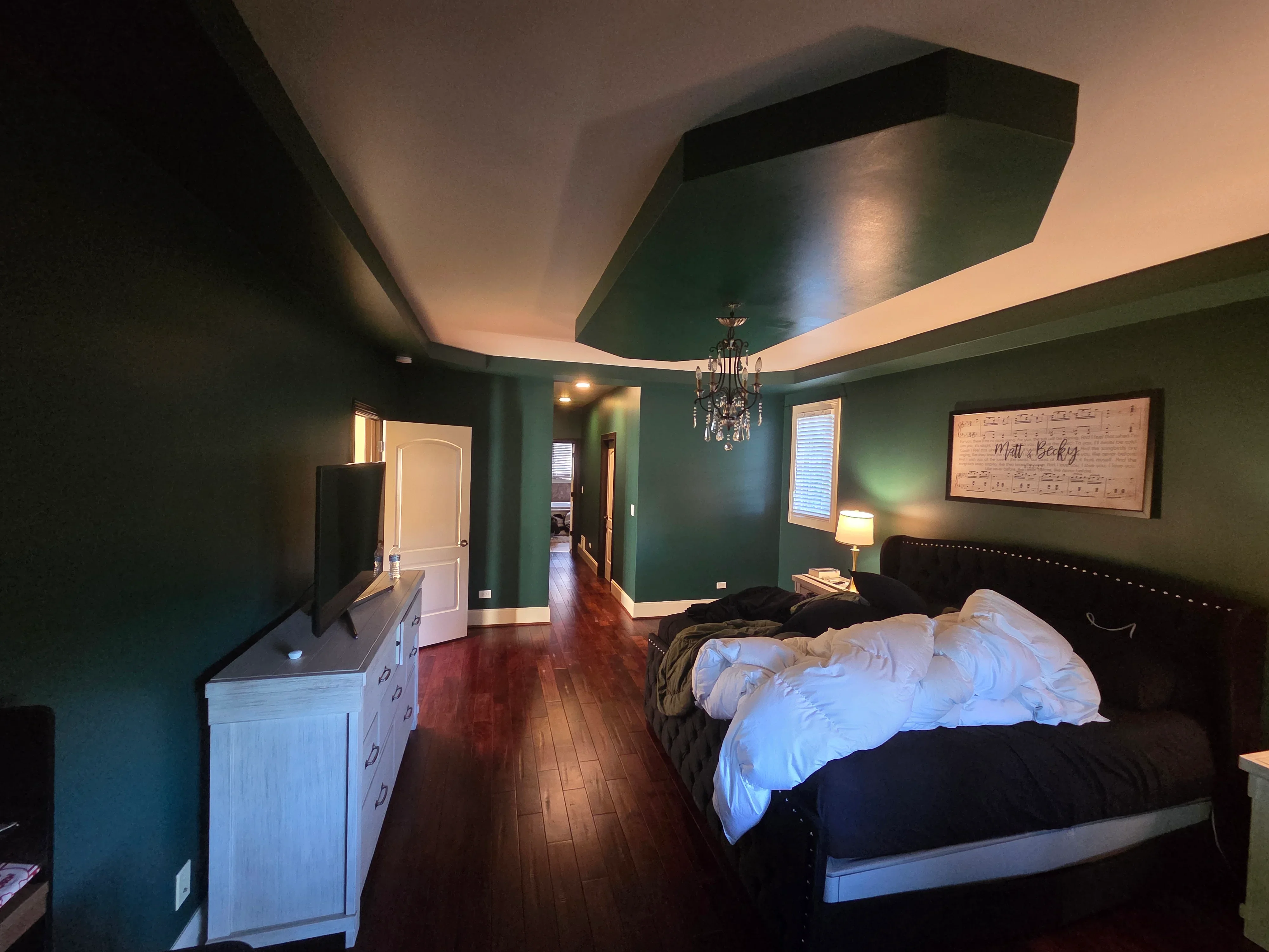 Master bedroom with forest green walls, cream tray ceiling, hardwood floors, and professional interior paint finish