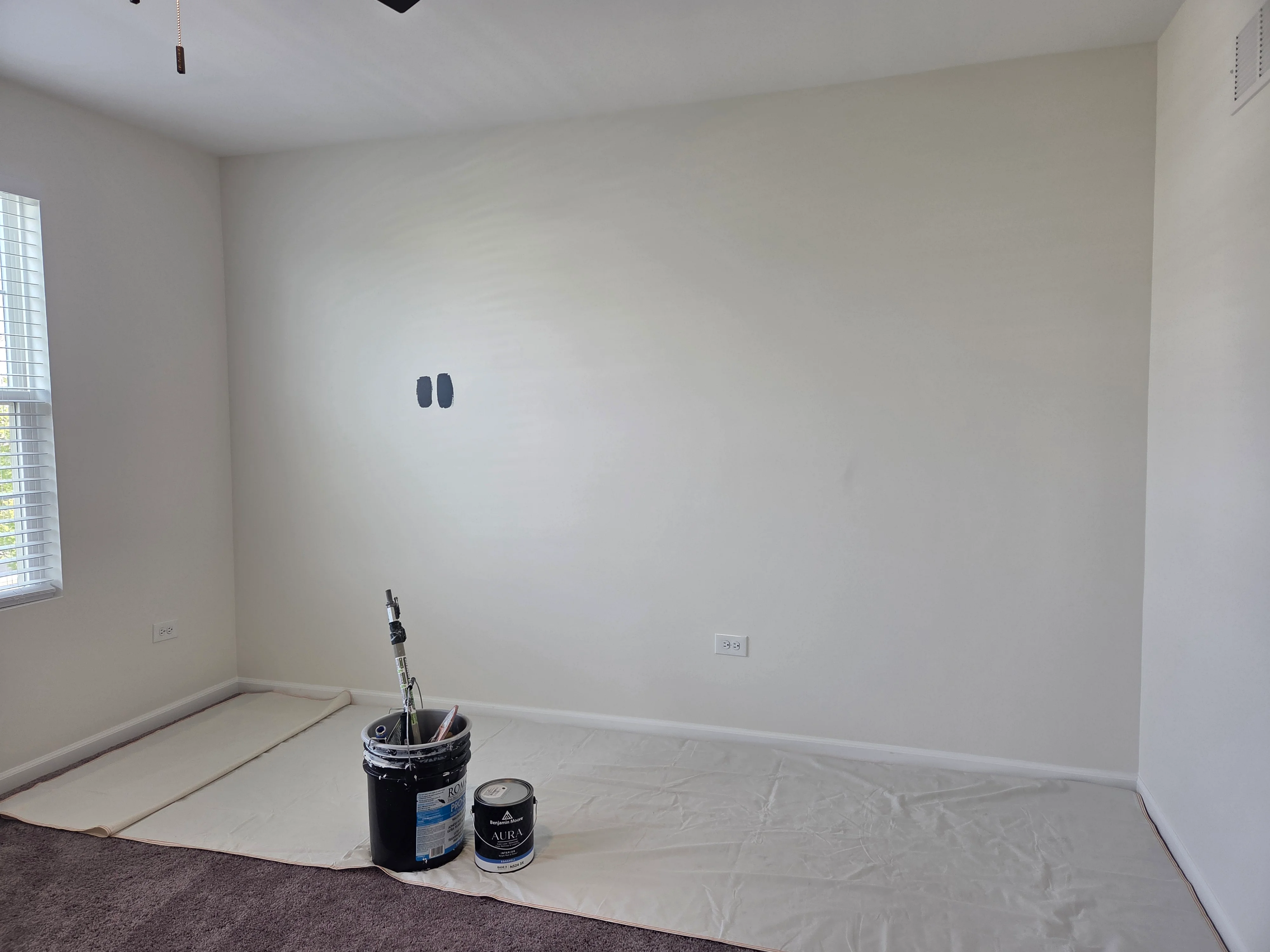 Interior room with taped drywall seams, paint cans, and drop cloth protection on floor