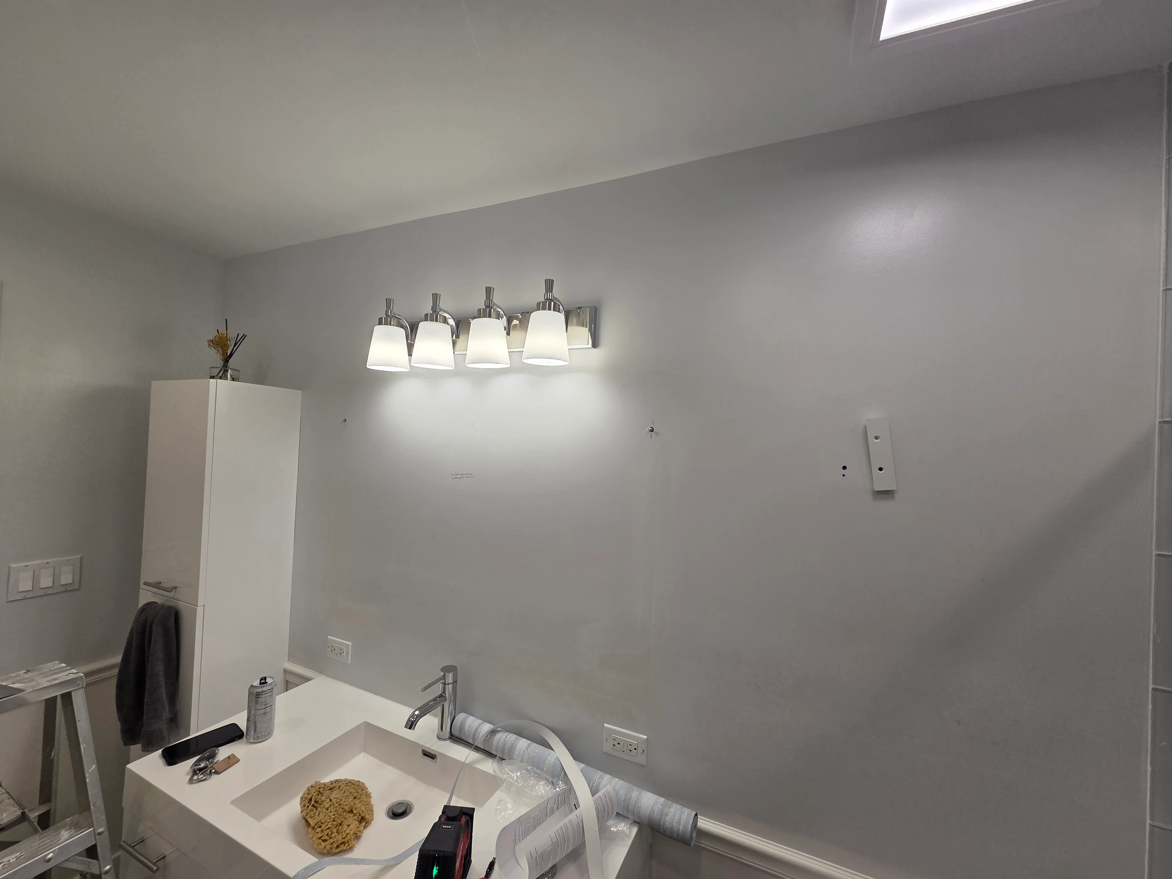 Bathroom with gray painted walls, white ceiling, four-light vanity fixture, and white sink vanity