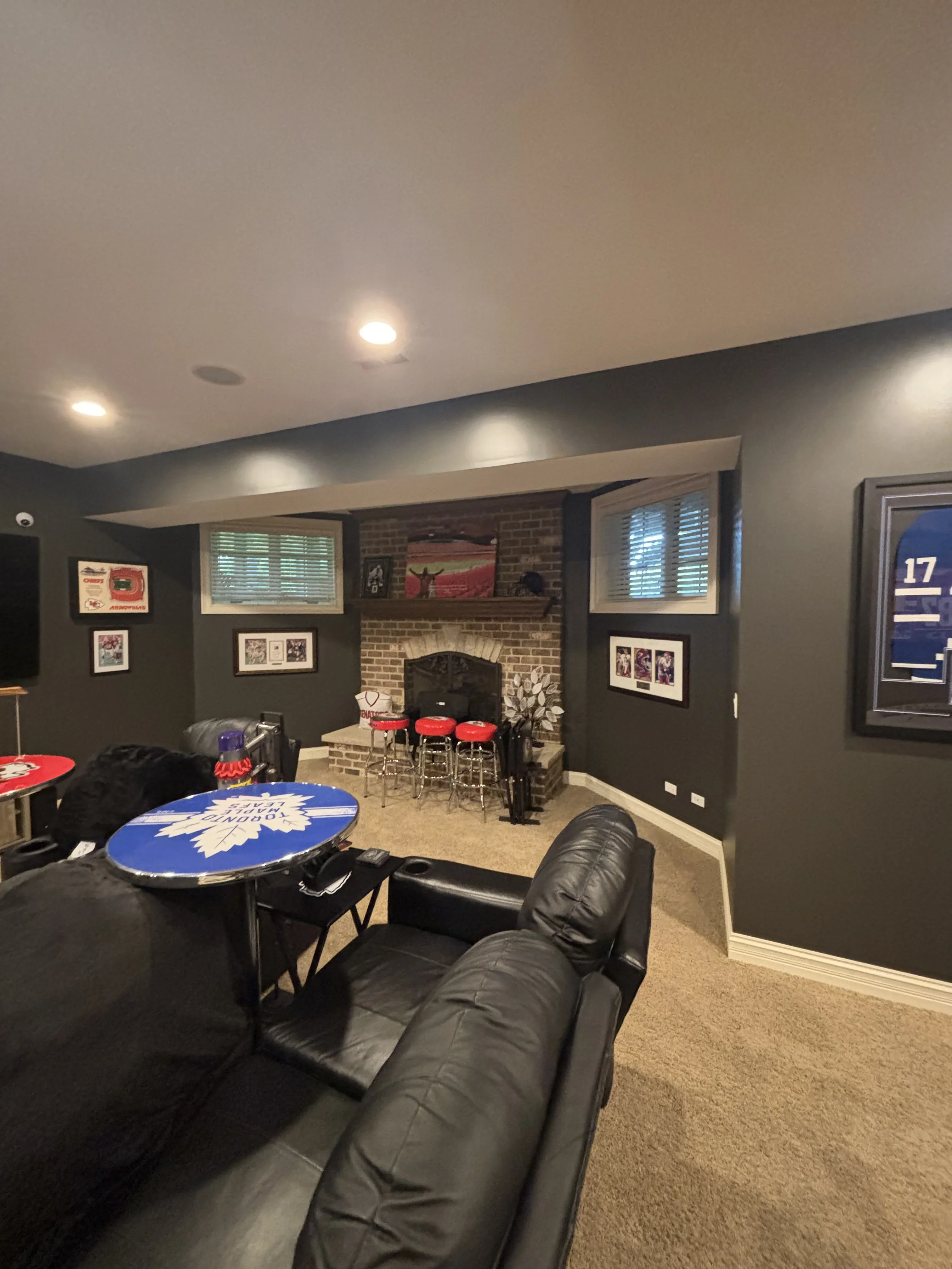 Dark charcoal painted walls with white trim, recessed lighting, and painted drywall soffits in finished basement recreation room
