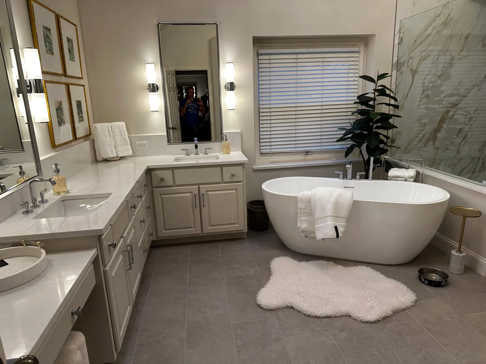 Master bathroom with neutral painted walls, painted cabinetry, marble tile accents, and white soaking tub