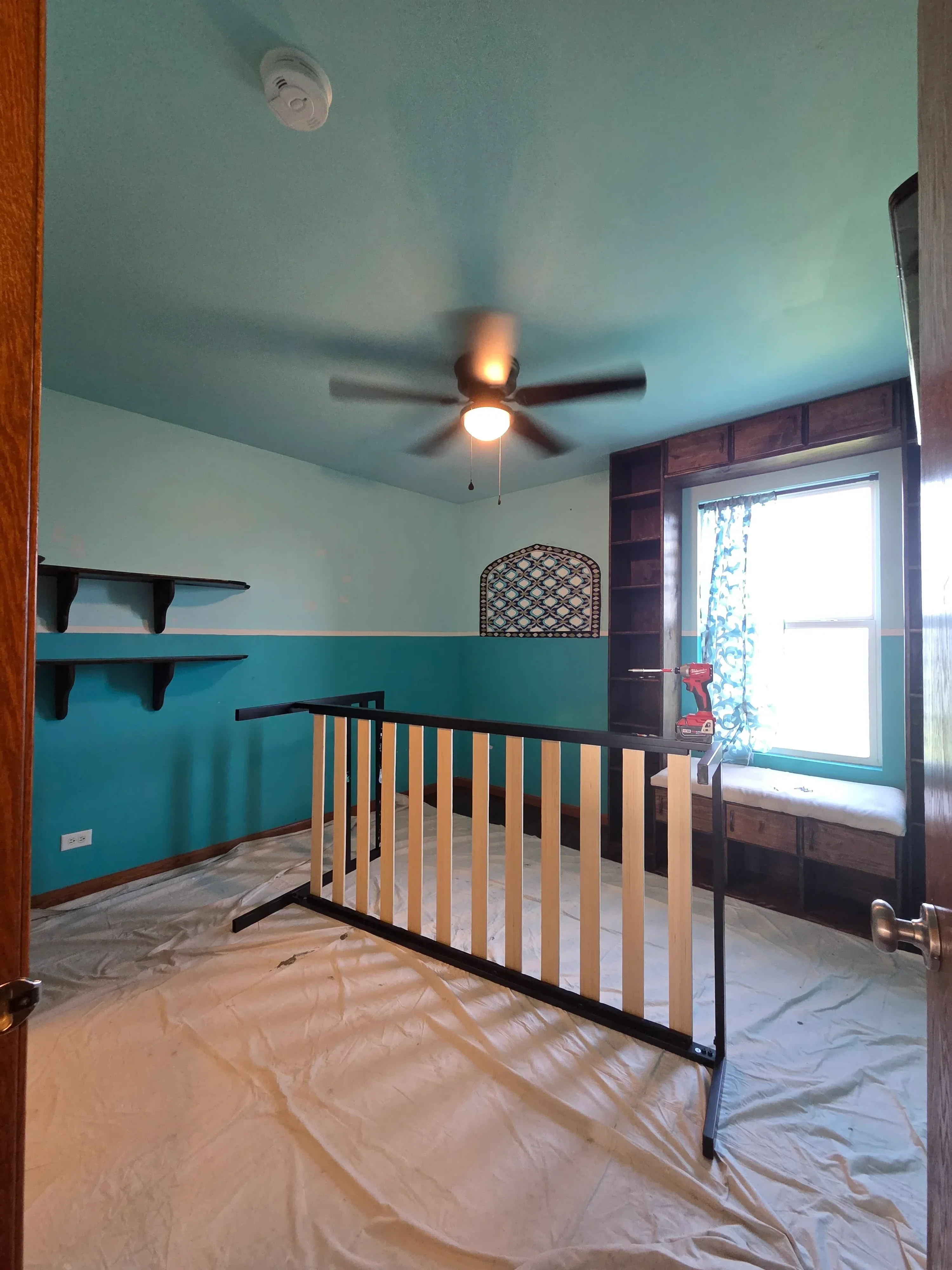 Turquoise and green painted bedroom walls with white trim and wooden bed frame