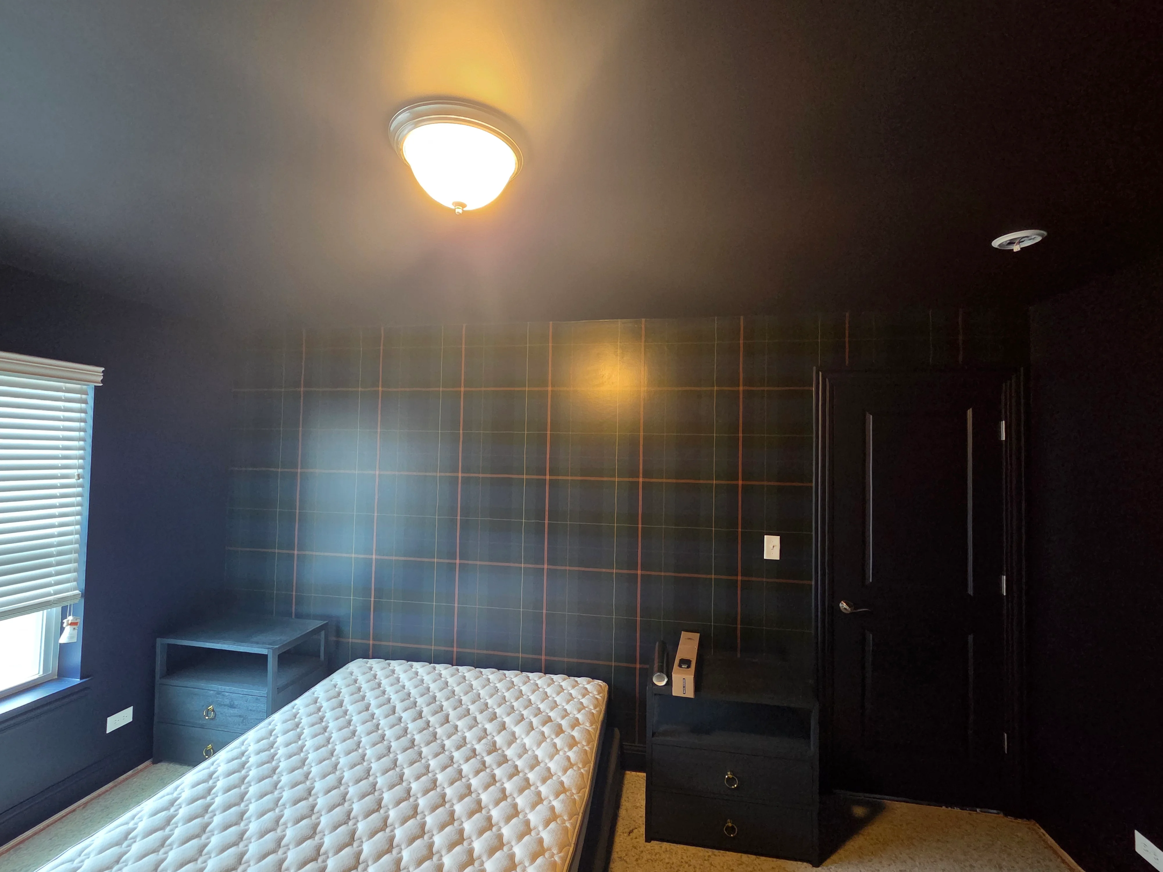 Dark blue bedroom with geometric plaid accent wall, painted ceiling, and recessed lighting