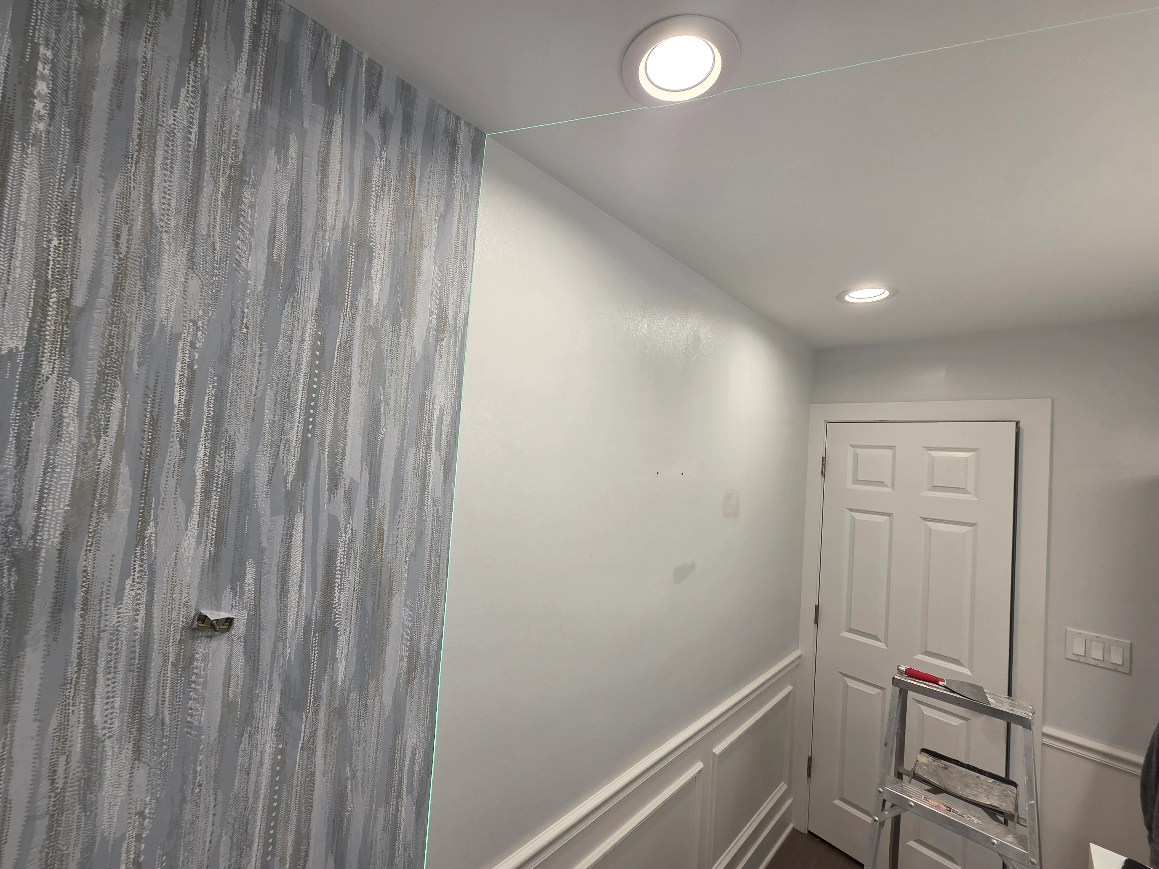 Gray striped wallpaper accent wall with white painted walls, recessed lighting, and white trim molding