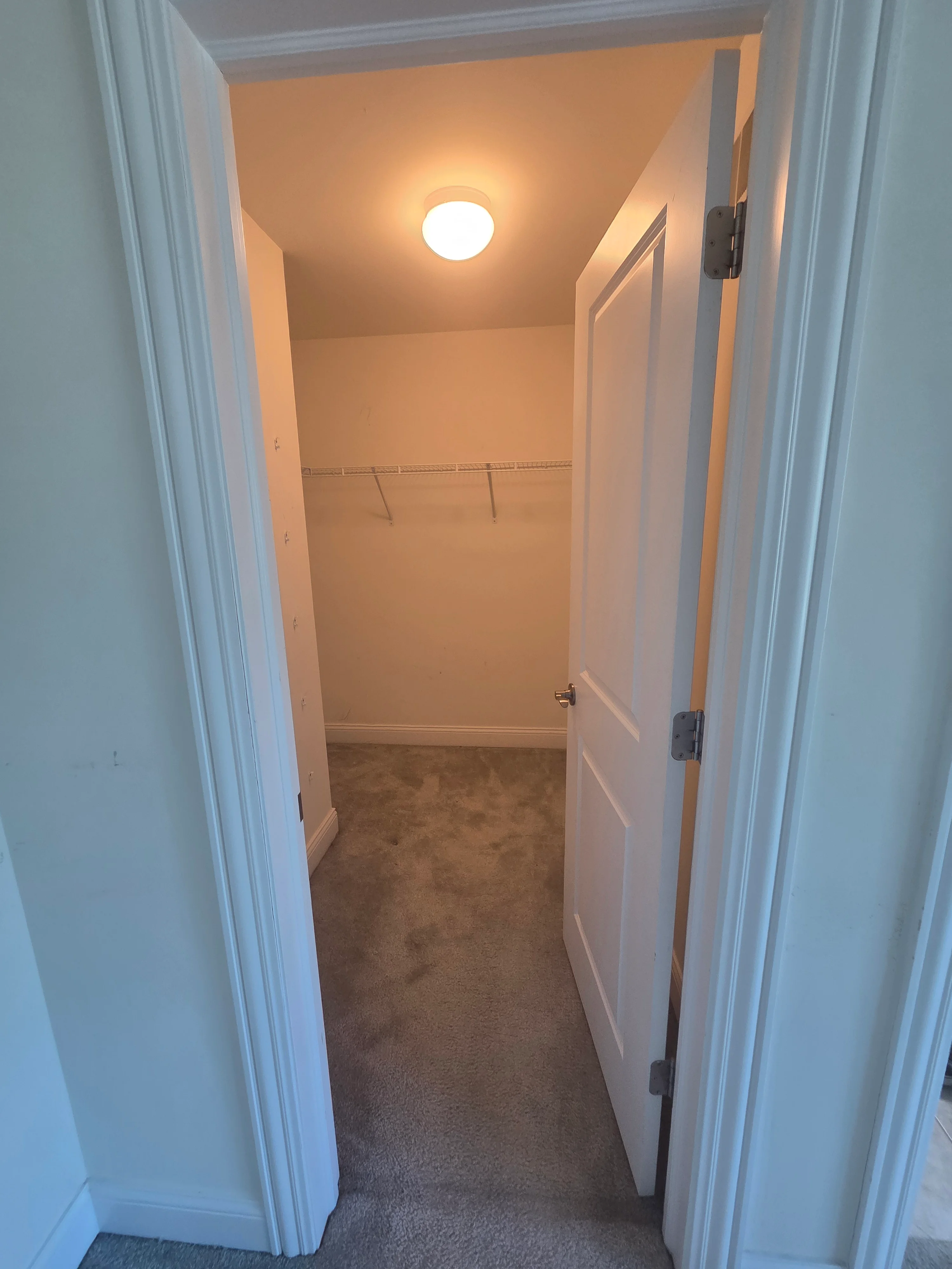 Painted walk-in closet with cream walls, white trim, and recessed lighting