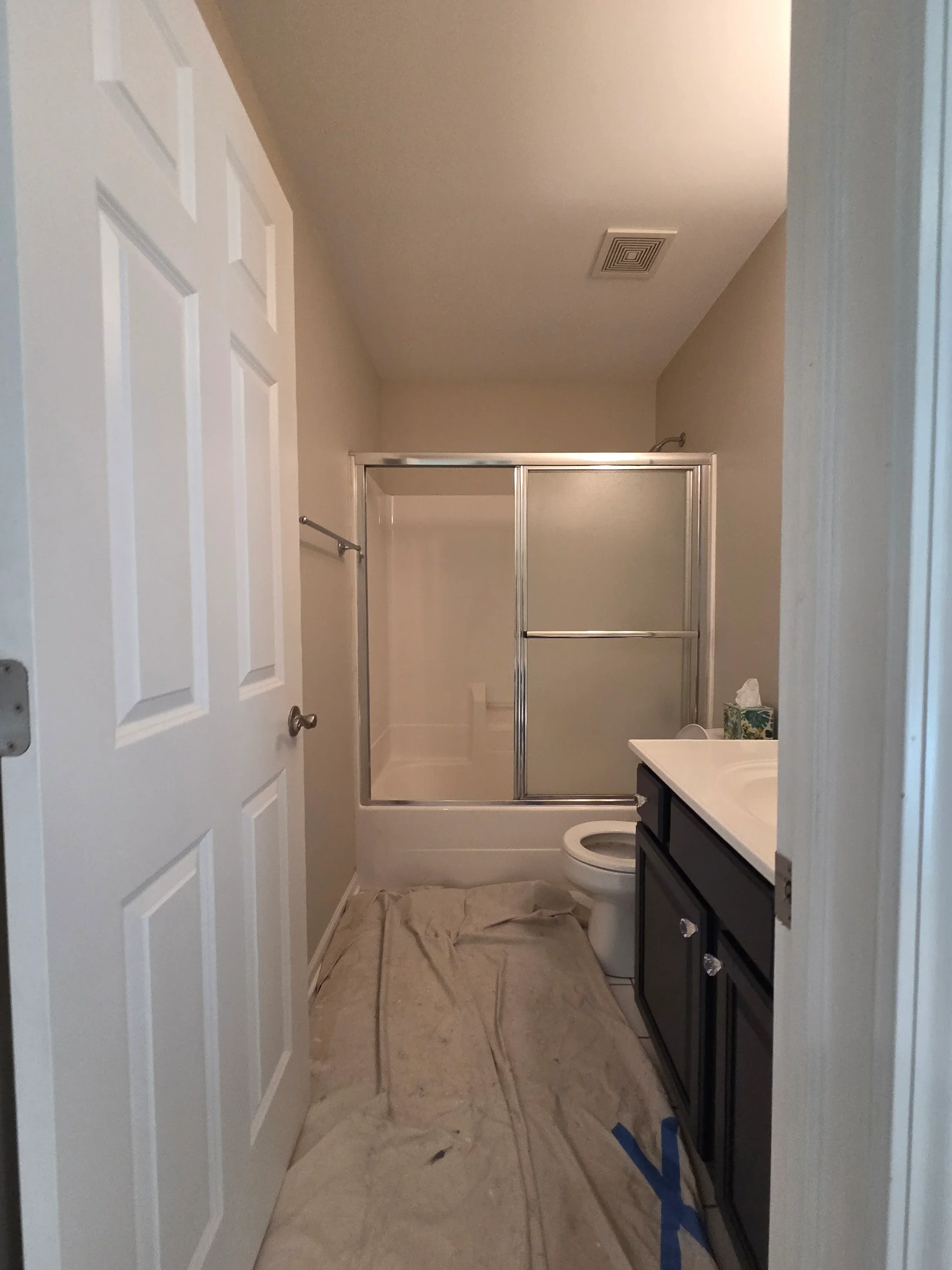 Finished bathroom with painted drywall, shower frame, and white painted walls and ceiling