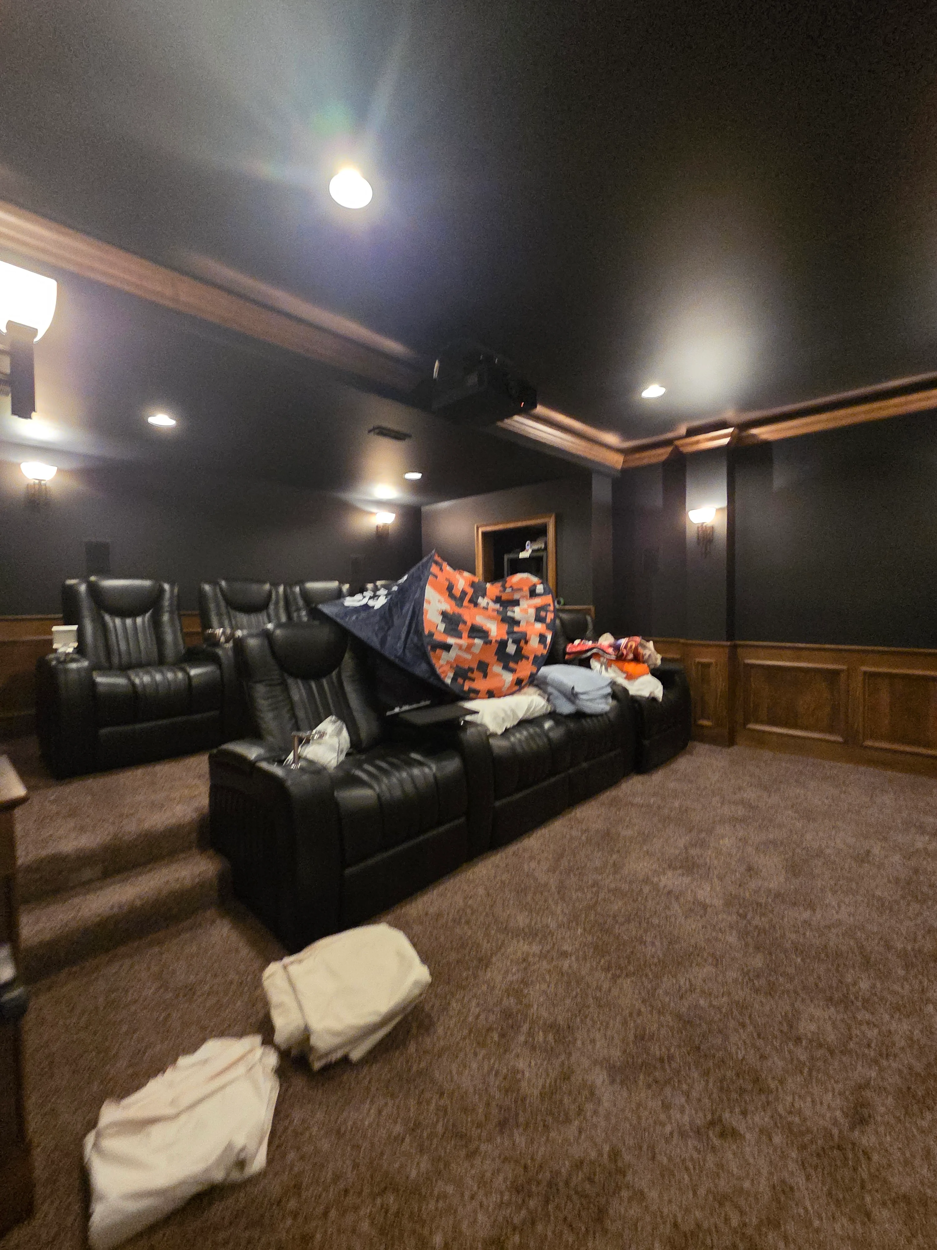 Dark gray painted walls with wood wainscoting, crown molding, and recessed lighting in home theater room
