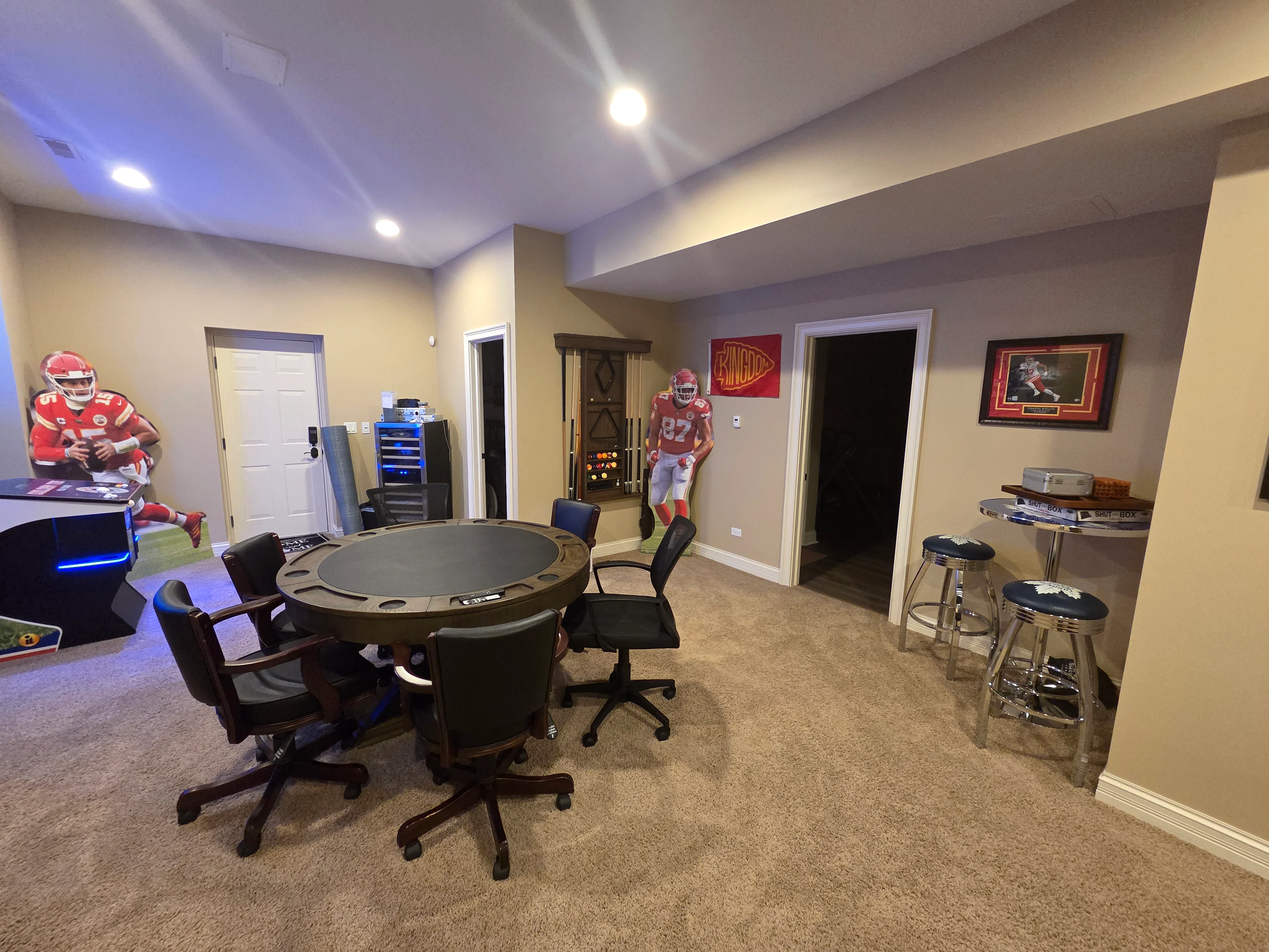 Finished basement room with beige painted walls, gray ceiling, recessed lights, and sports-themed decor