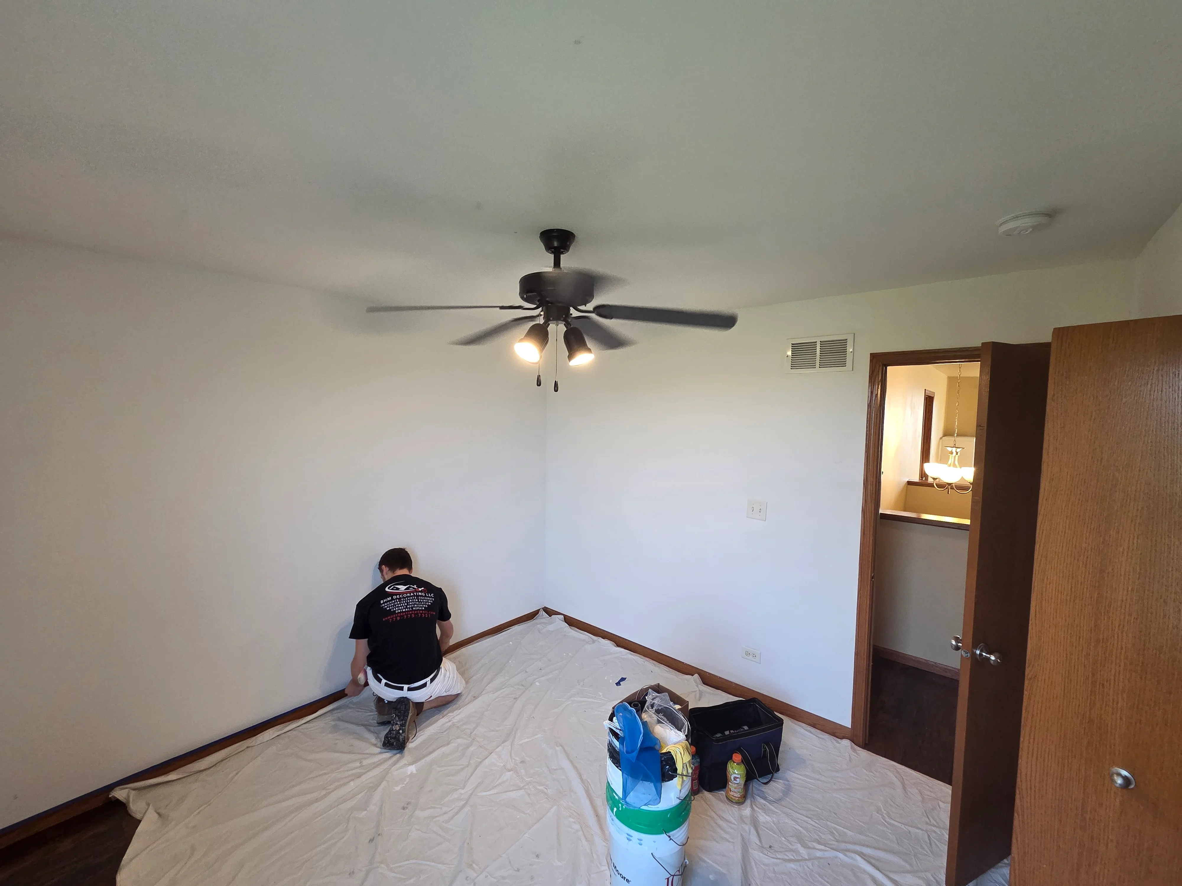 Freshly painted bedroom with white walls and ceiling, ceiling fan with lights installed