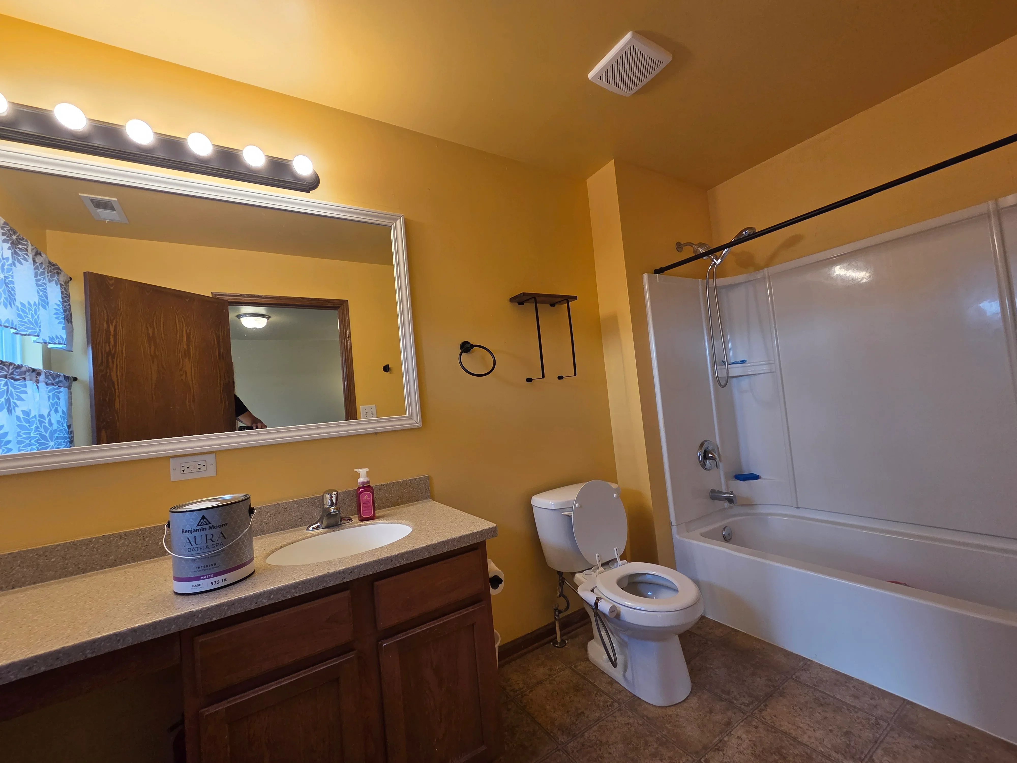 Bathroom with golden-yellow painted walls, white trim, dark wood vanity, and tile flooring