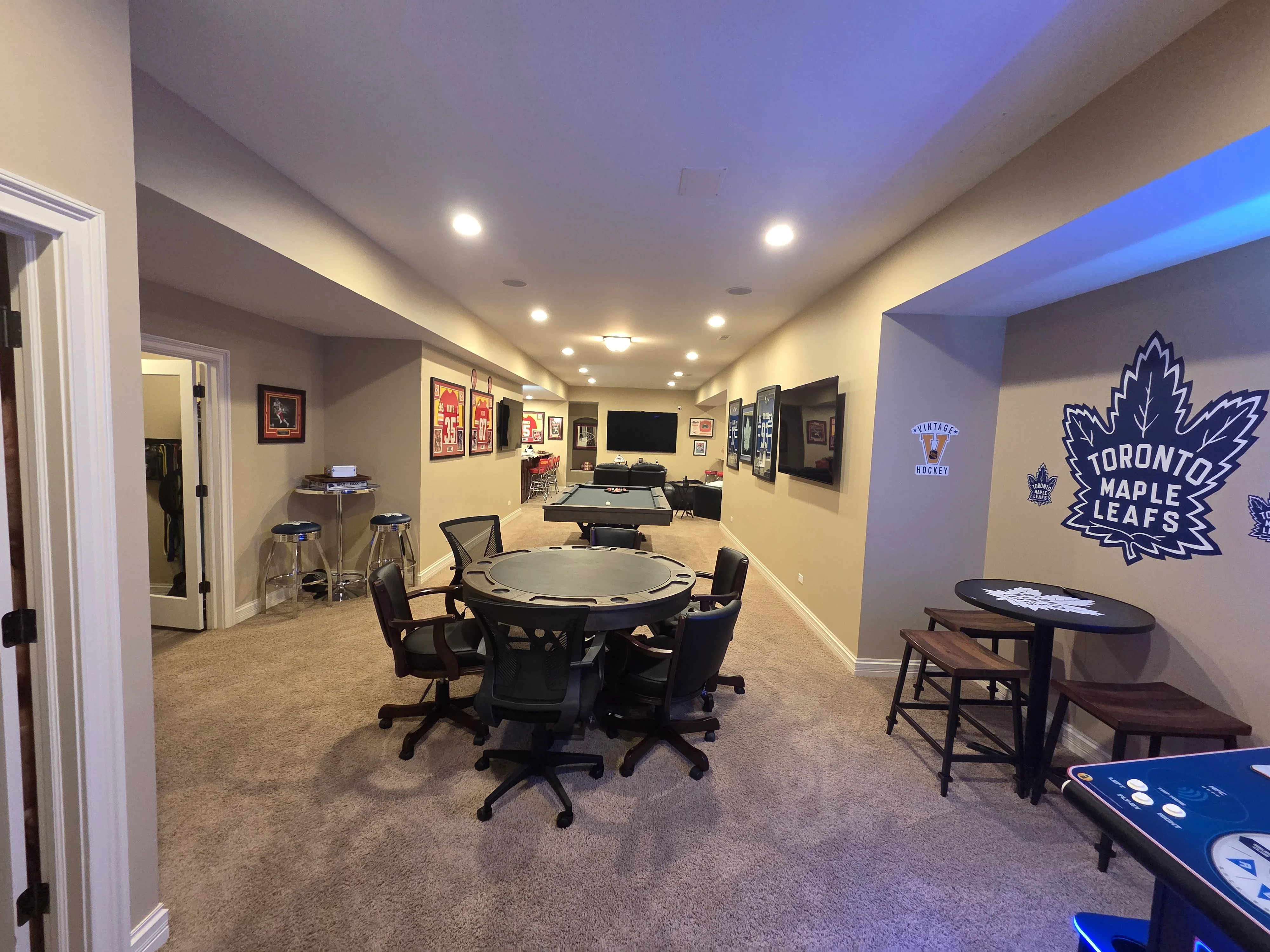 Finished basement recreation room with painted drywall, recessed lights, and blue accent lighting above bar area