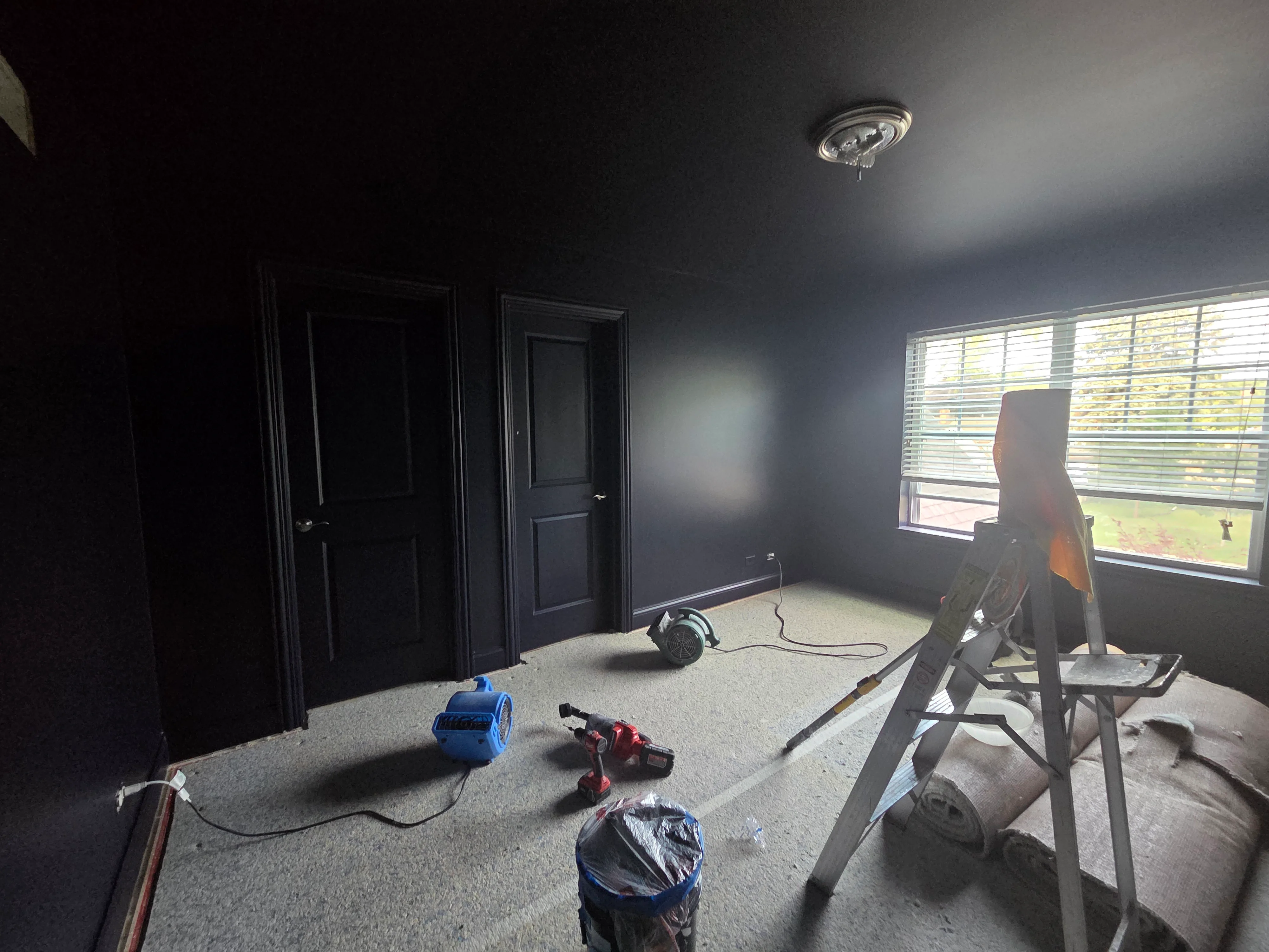 Dark gray painted bedroom walls and ceiling with black doors and recessed lighting