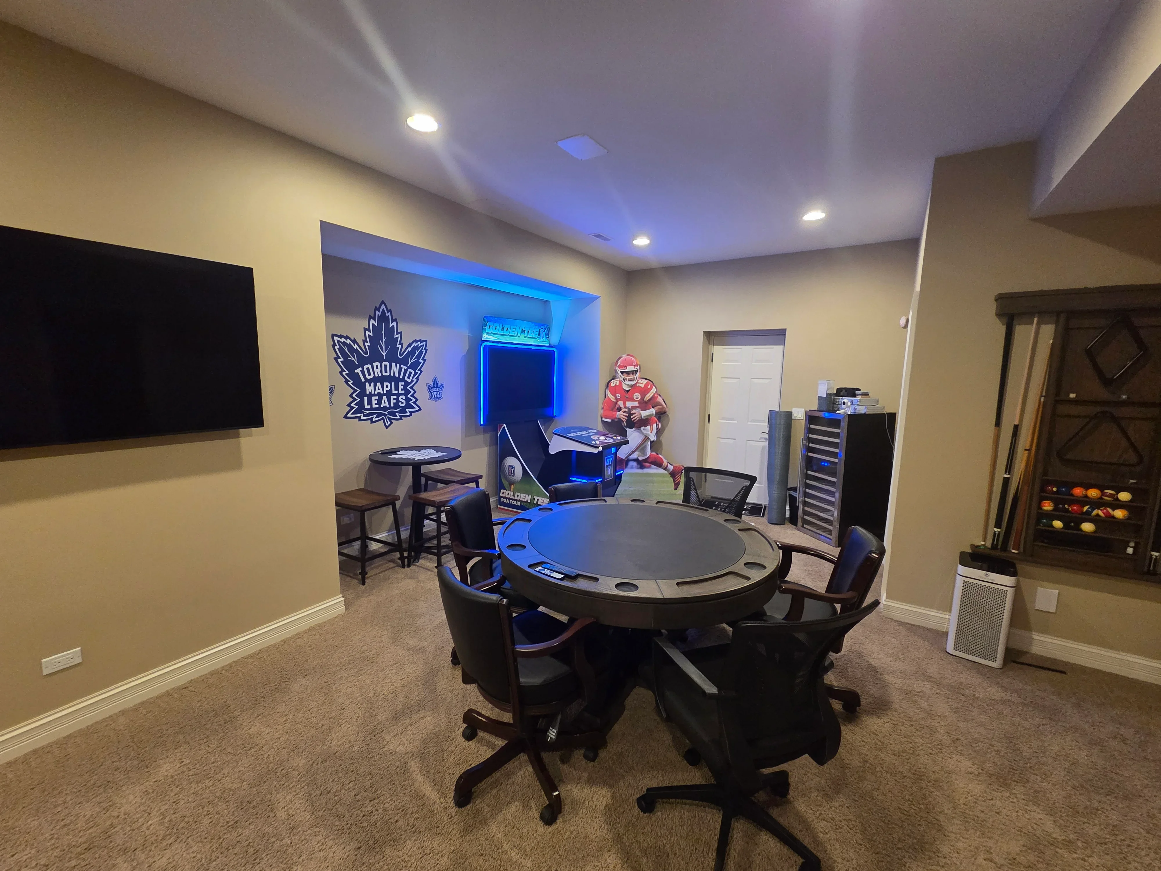 Beige recreation room with blue accent wall, recessed lighting, and neon accents