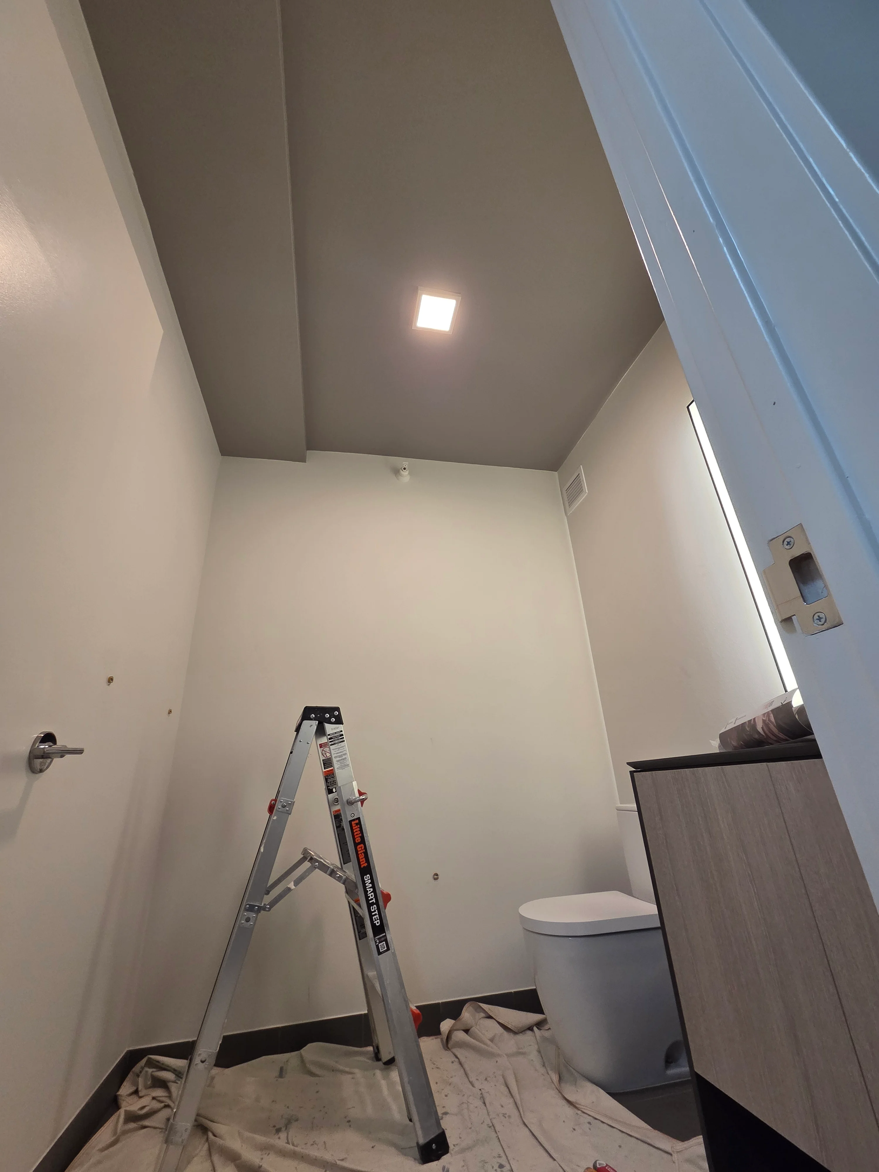 Bathroom with white painted walls, gray ceiling, recessed lighting, and white toilet fixture