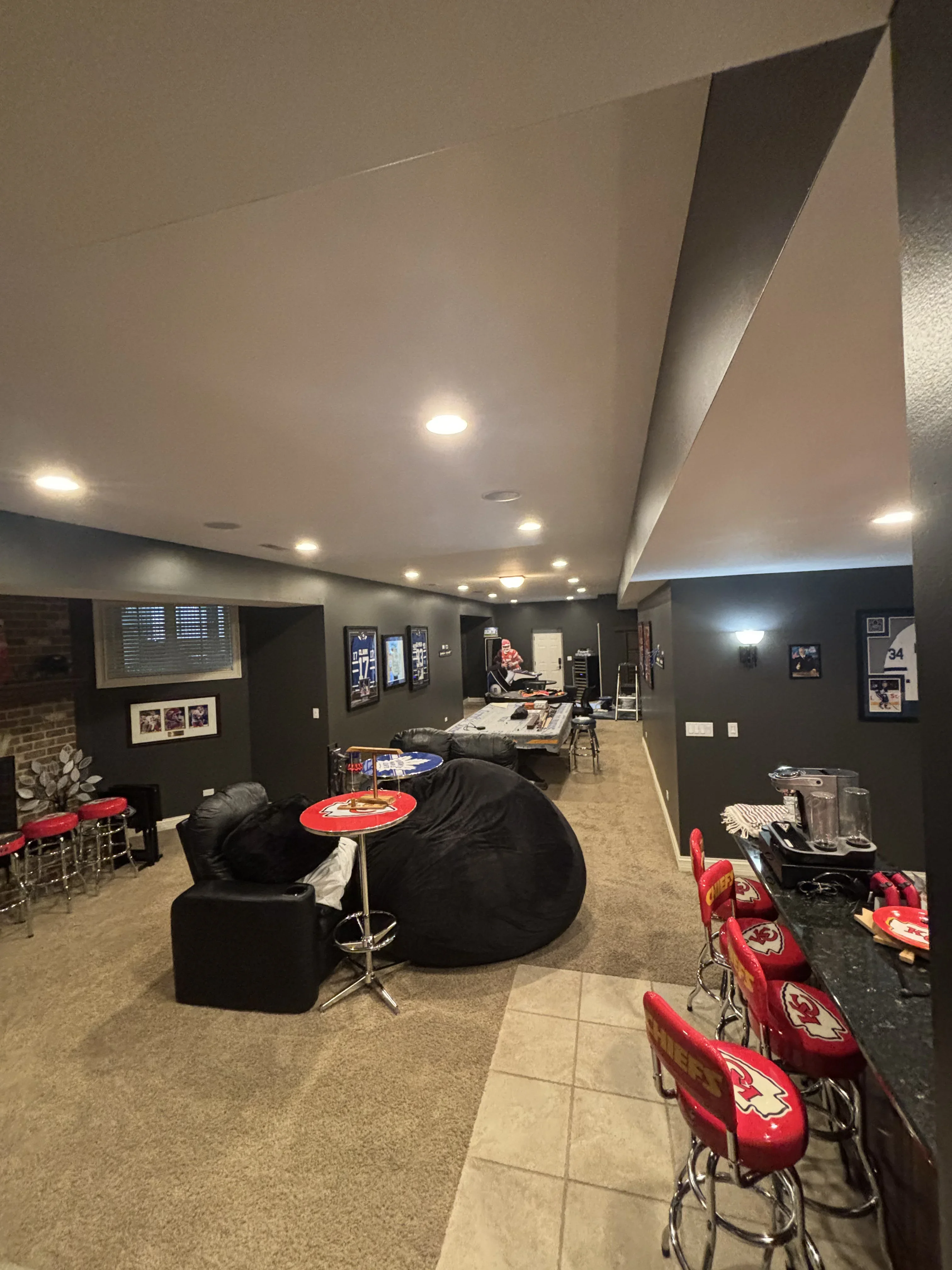 Finished basement with dark charcoal walls, white ceiling, recessed lighting, and drywall soffit details