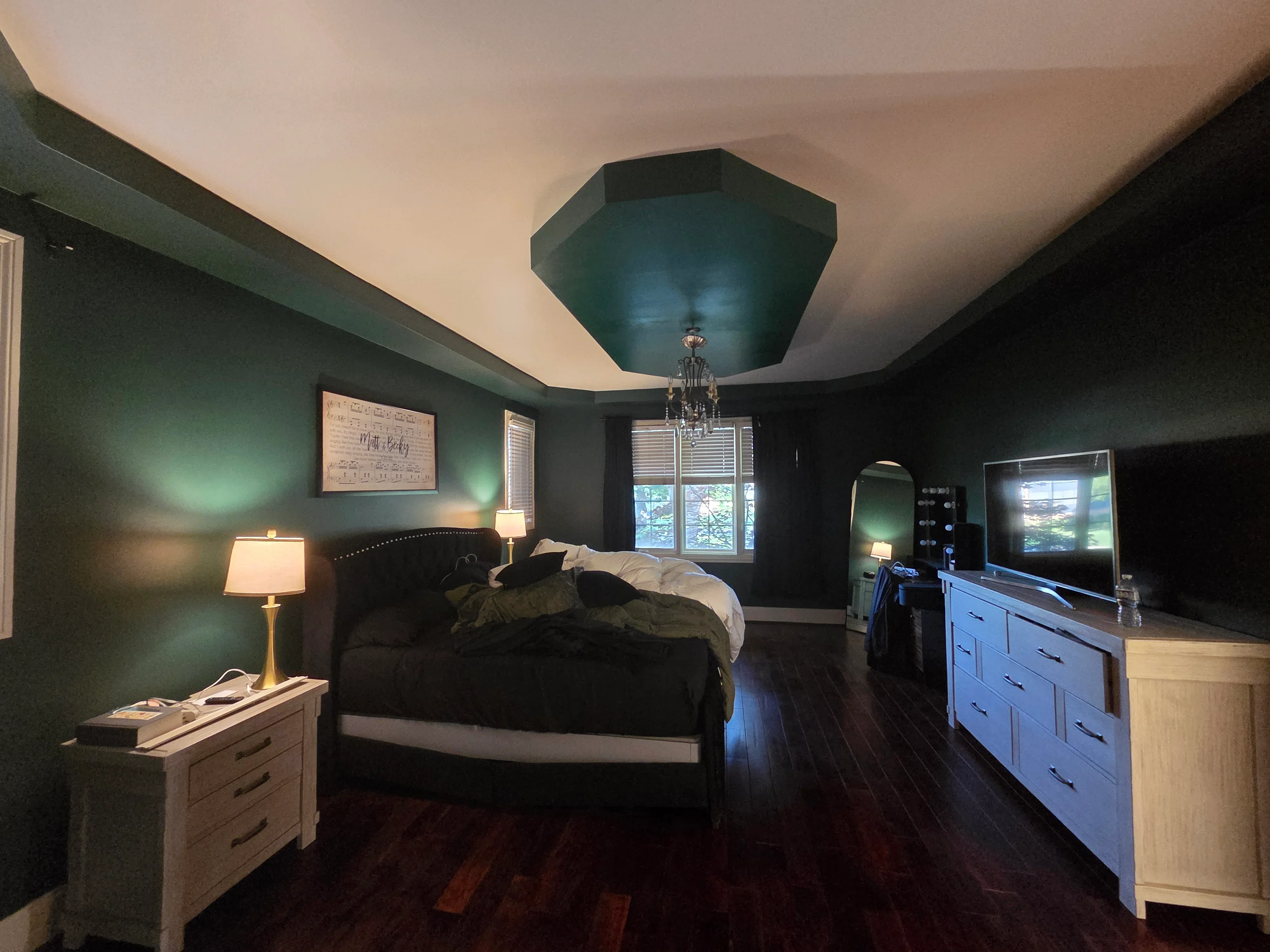 Master bedroom with forest green walls, cream ceiling, and teal geometric tray ceiling detail