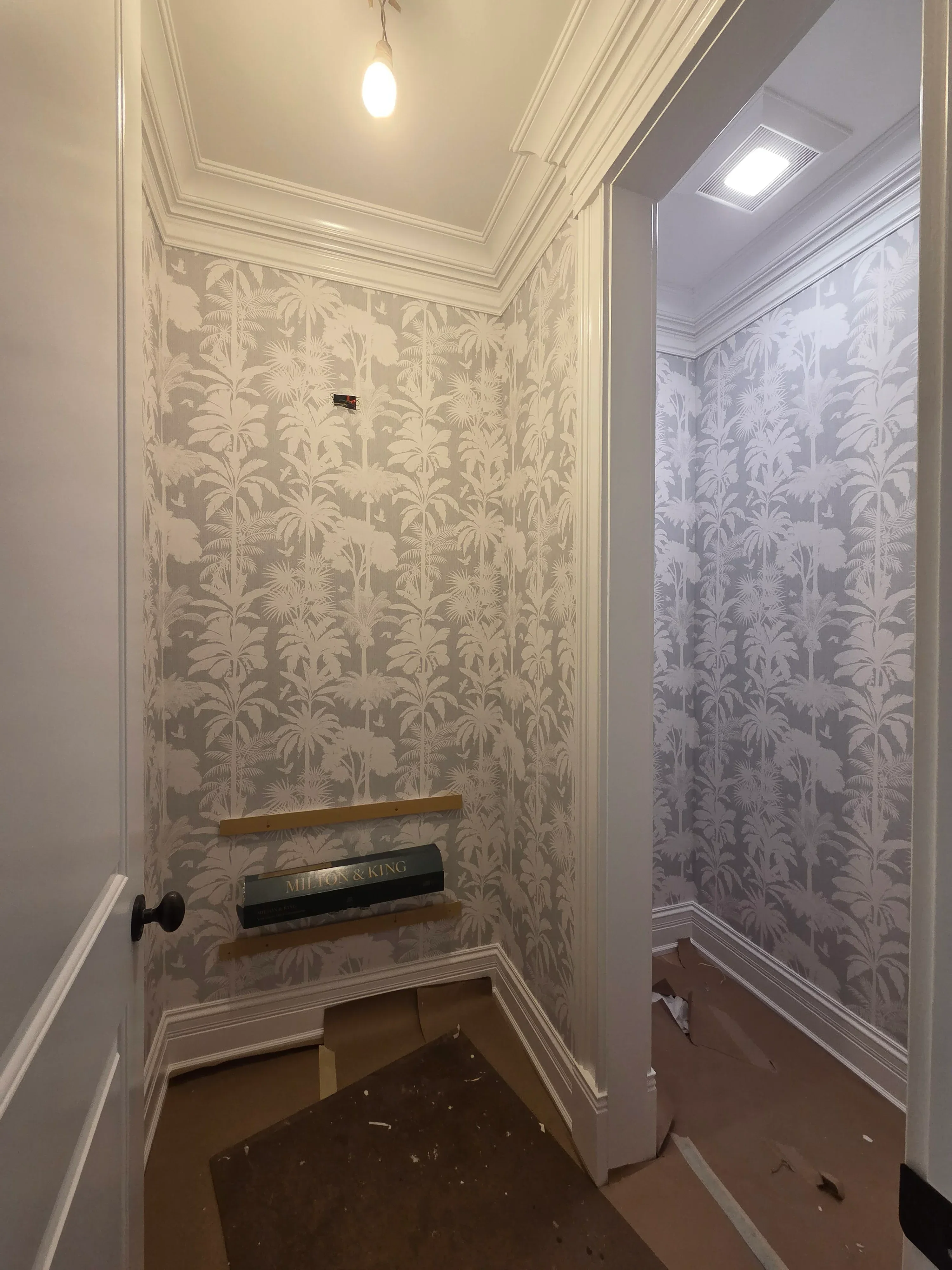 Damask wallpaper with white crown molding and recessed lighting in finished room