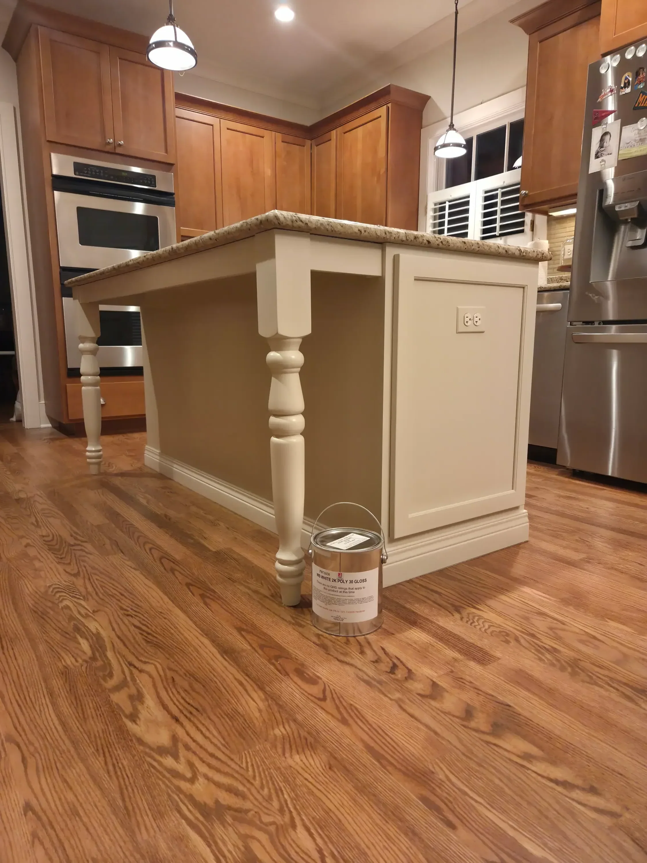 Cream painted kitchen cabinets with white trim and turned spindle details on wood flooring