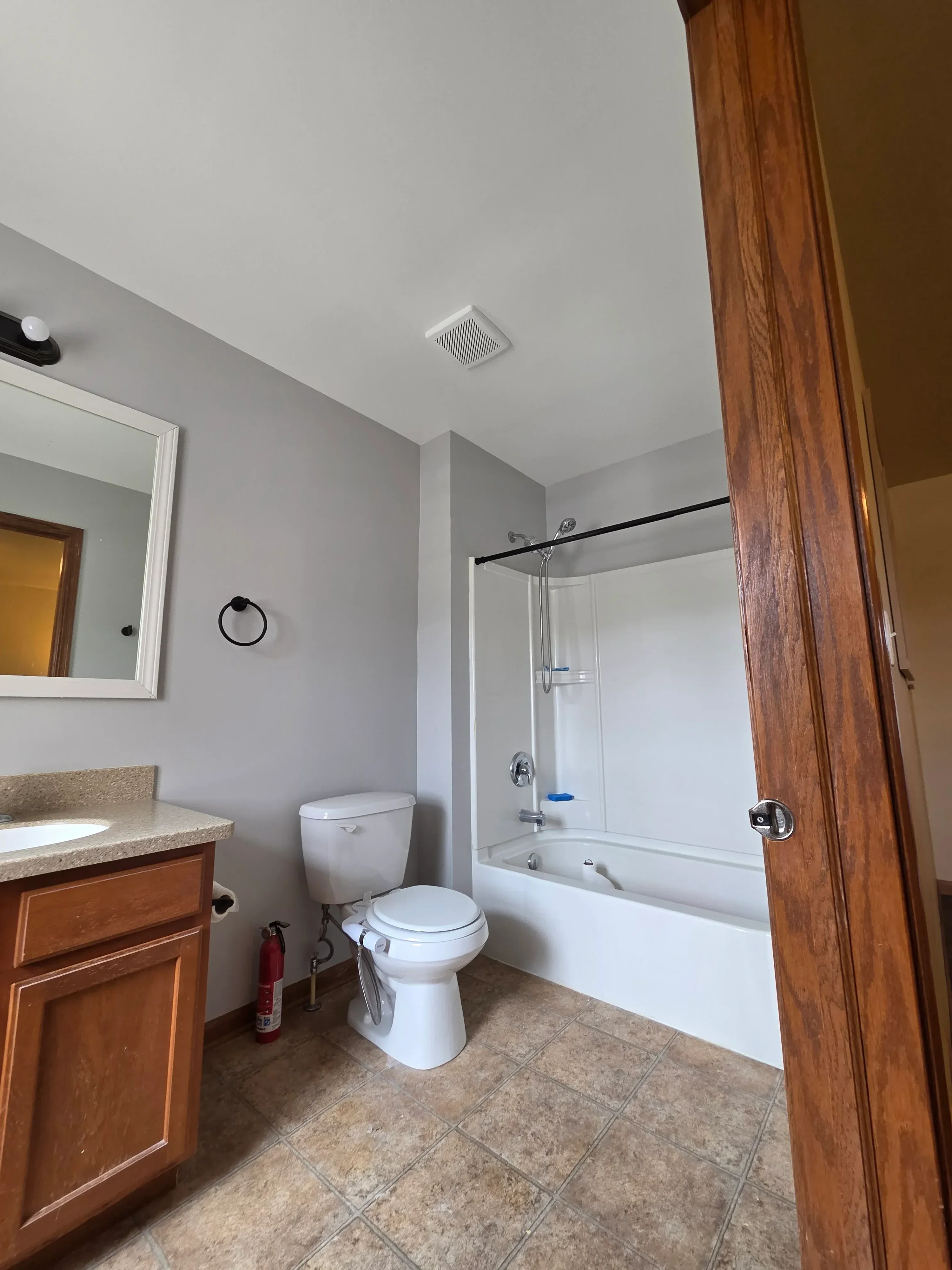 Freshly painted white bathroom with wood beam trim, tile surround, and vanity area