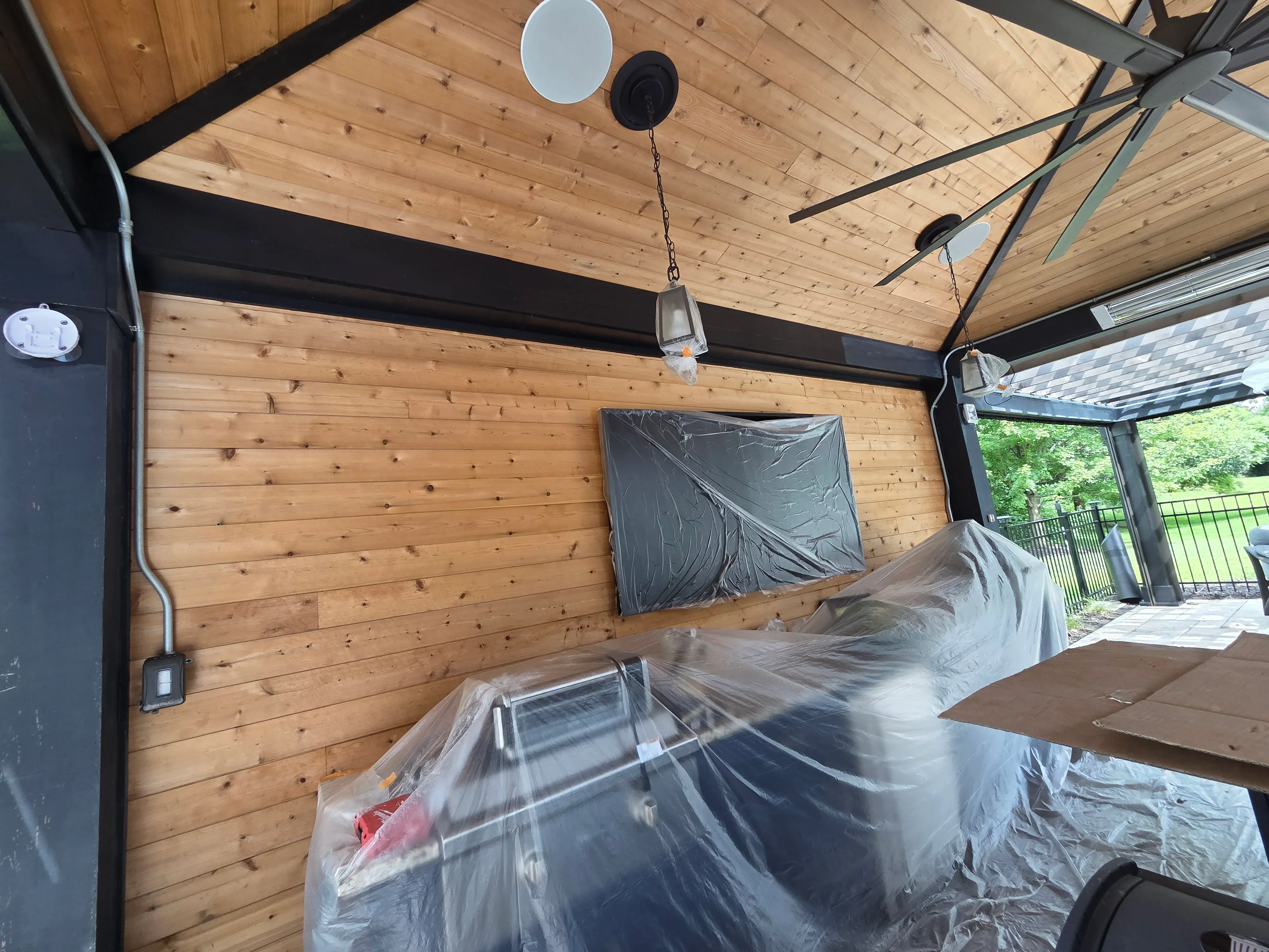 Log cabin interior with protective plastic coverings, primed walls, and exposed wood beam ceiling