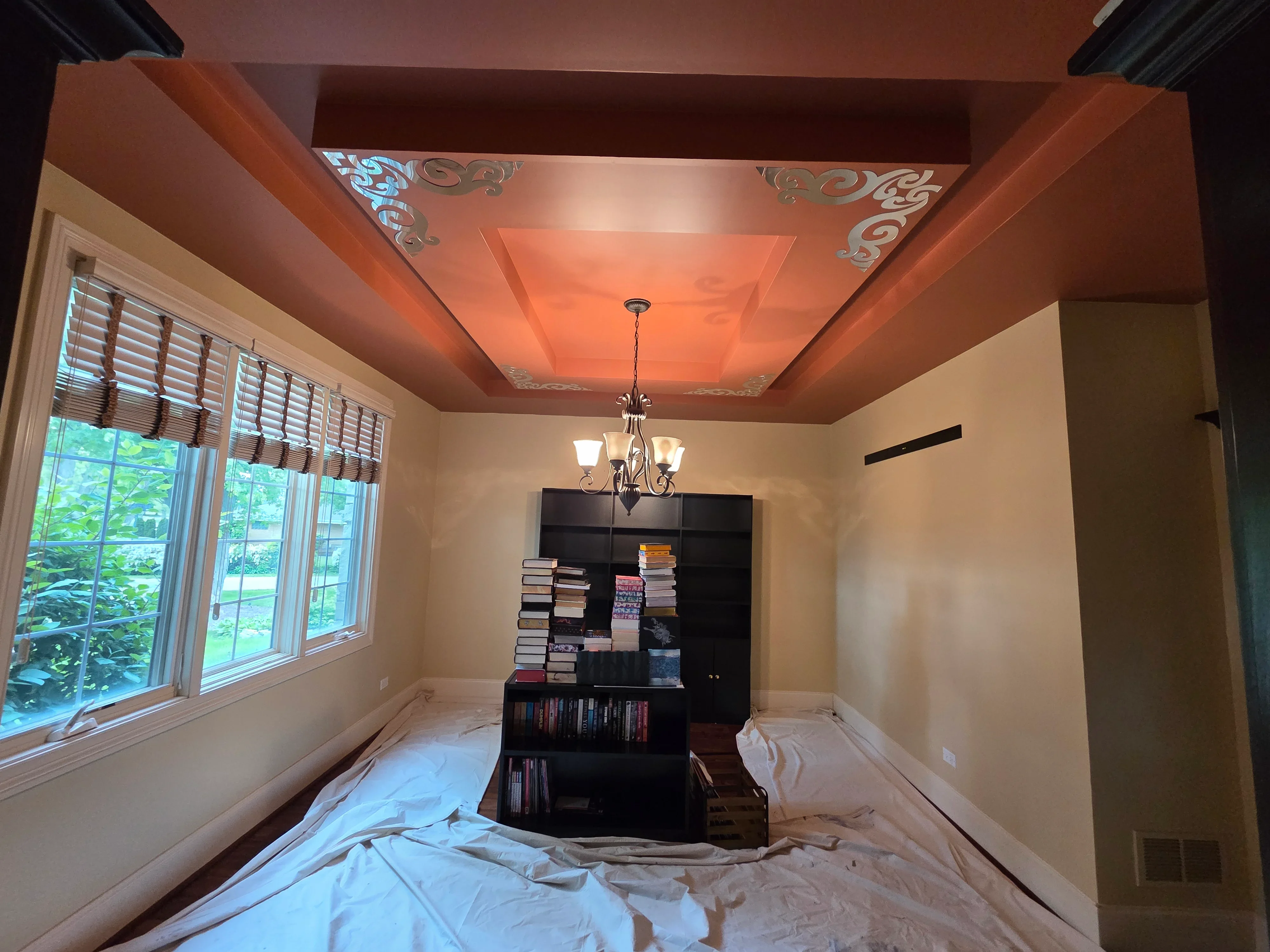 Terracotta coffered ceiling with stenciled details, cream walls, and decorative chandelier