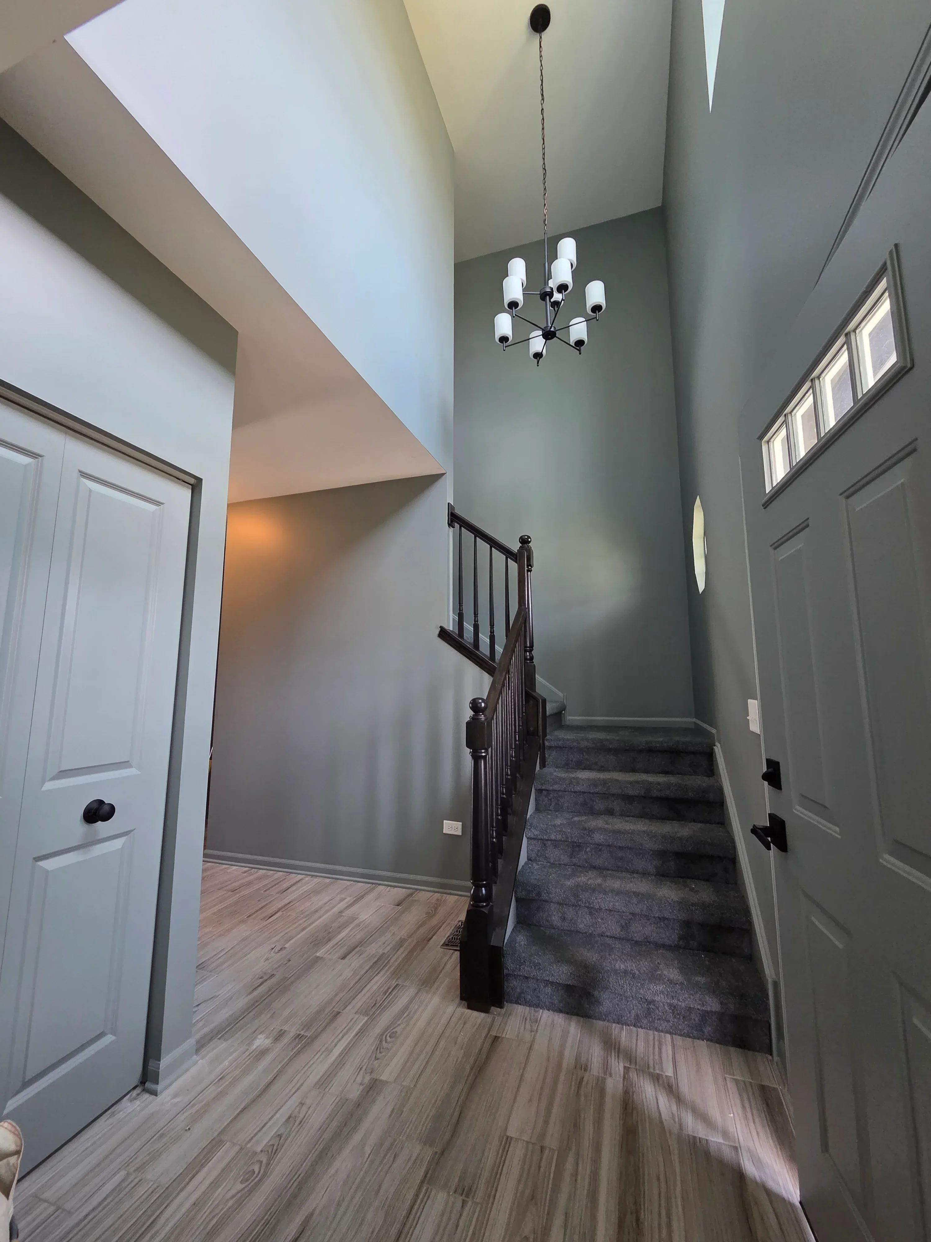 Gray painted bedroom with white trim, coffered ceiling, recessed lights, and wood-grain accent wall