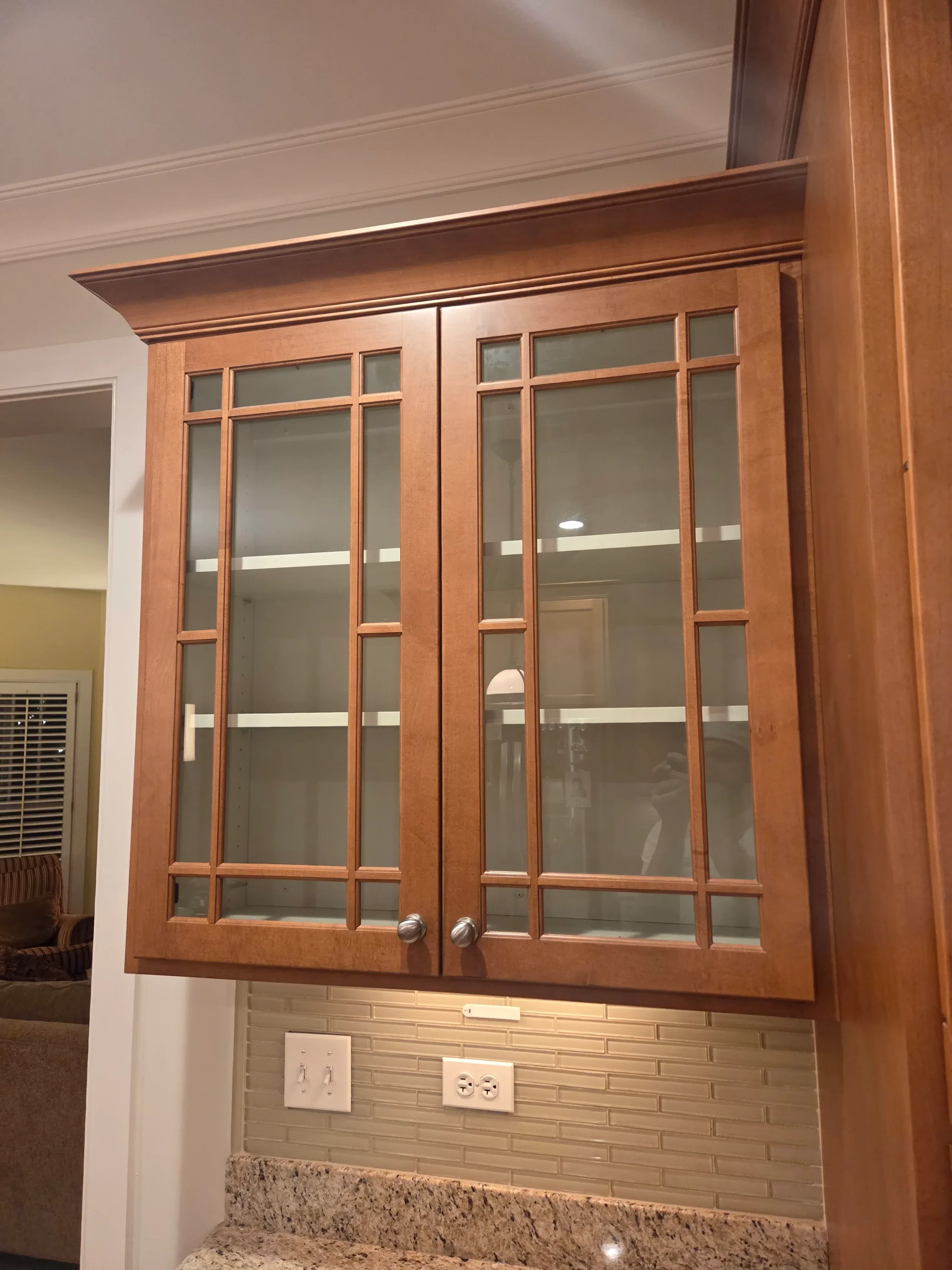 Stained wood cabinet doors with glass panels and chrome hardware in kitchen