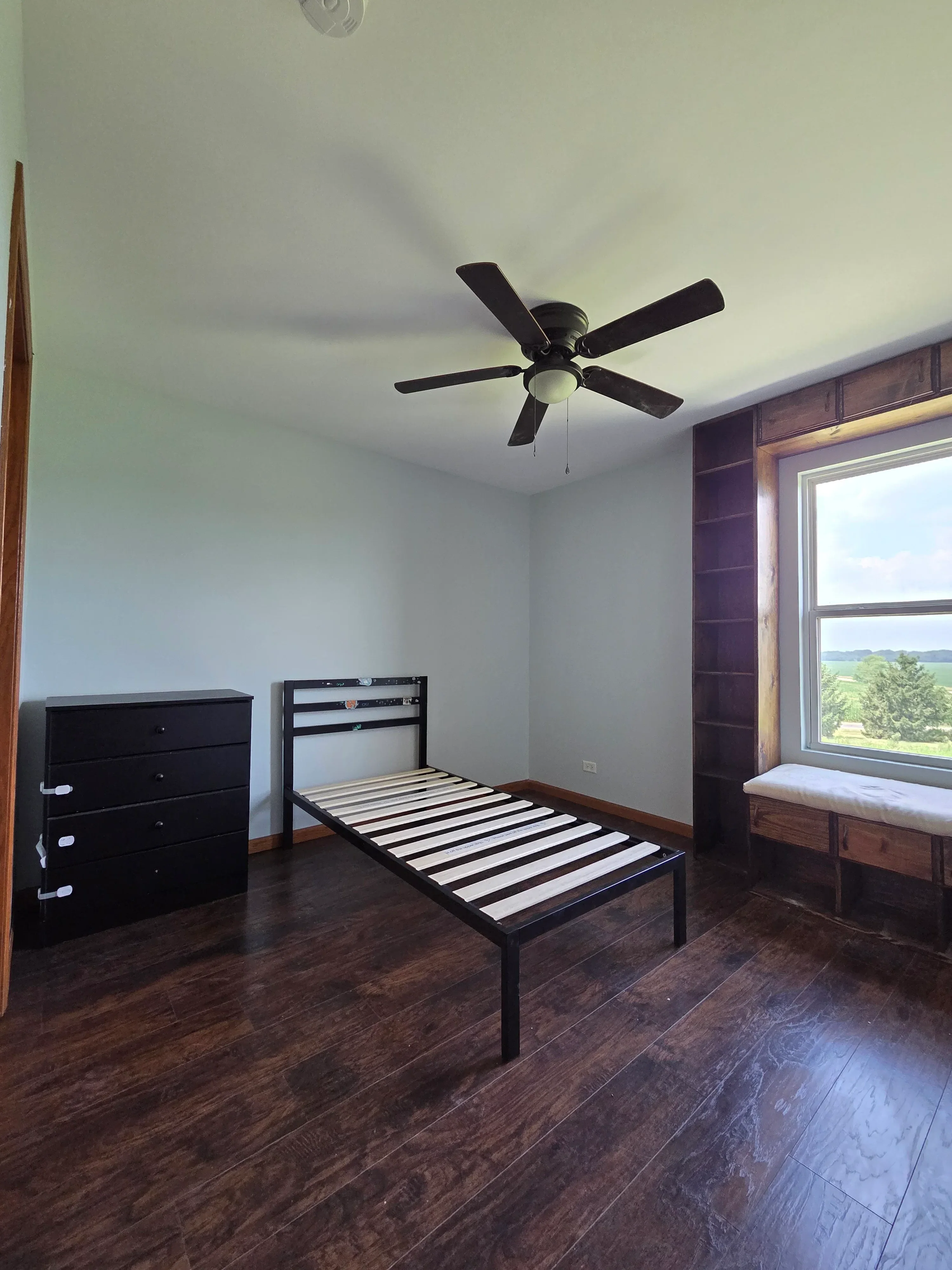 Interior room with painted white drywall walls, exposed wood beams, skylight, dark wood flooring, and white railing