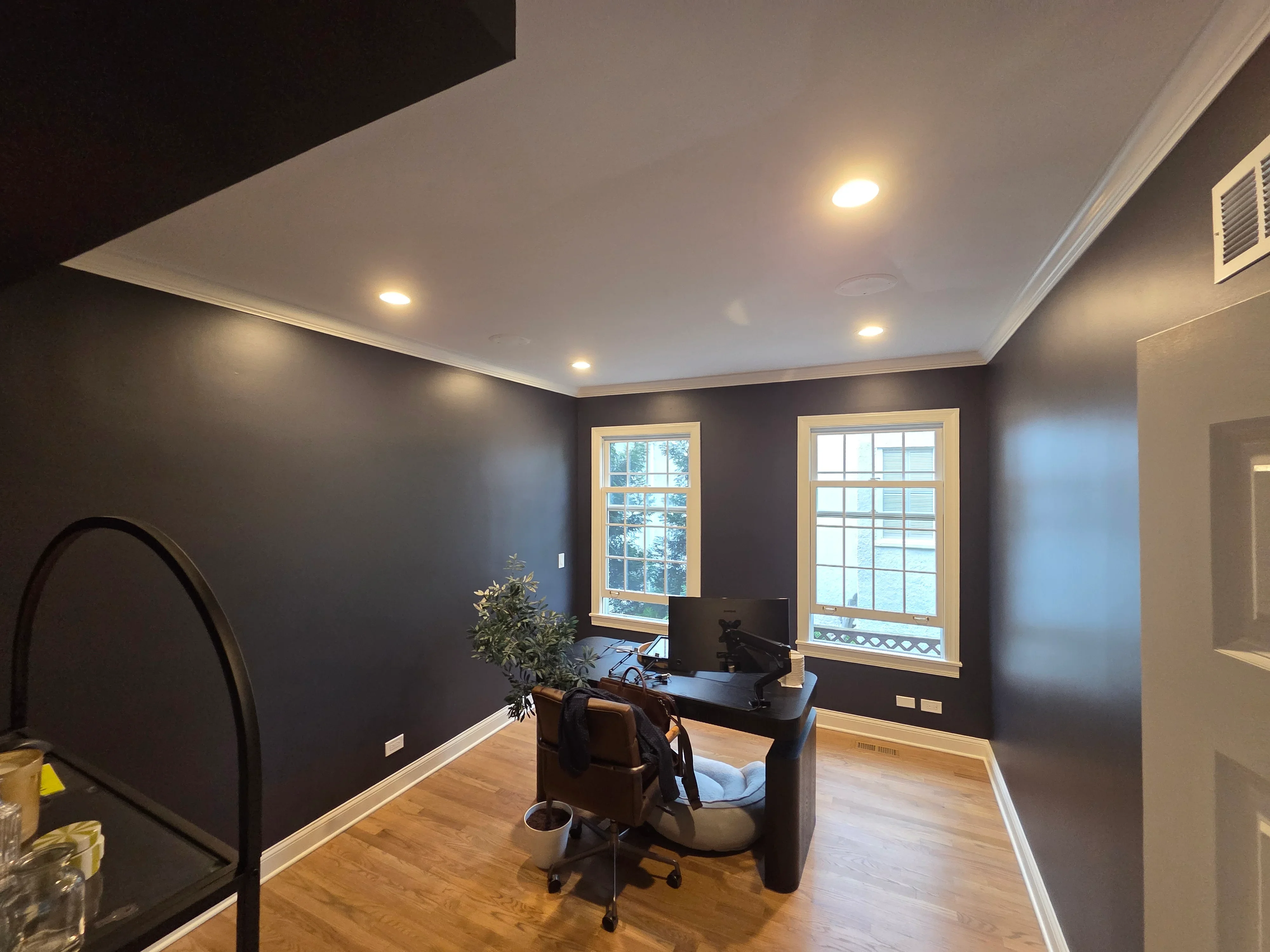 Dark charcoal painted office walls with white trim, recessed ceiling lights, and hardwood floors