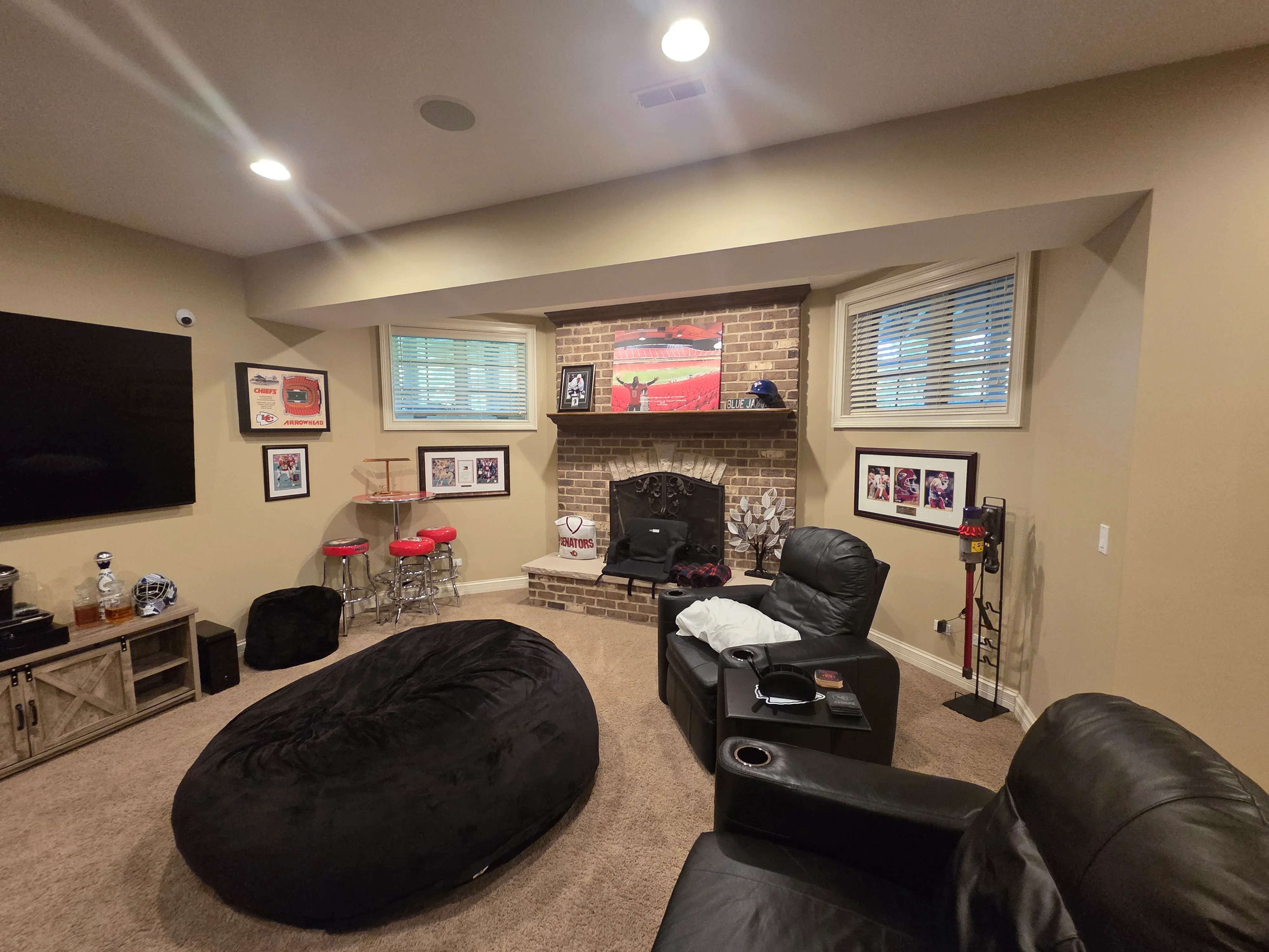Painted basement room with neutral walls, white ceiling, recessed lighting, and exposed brick fireplace