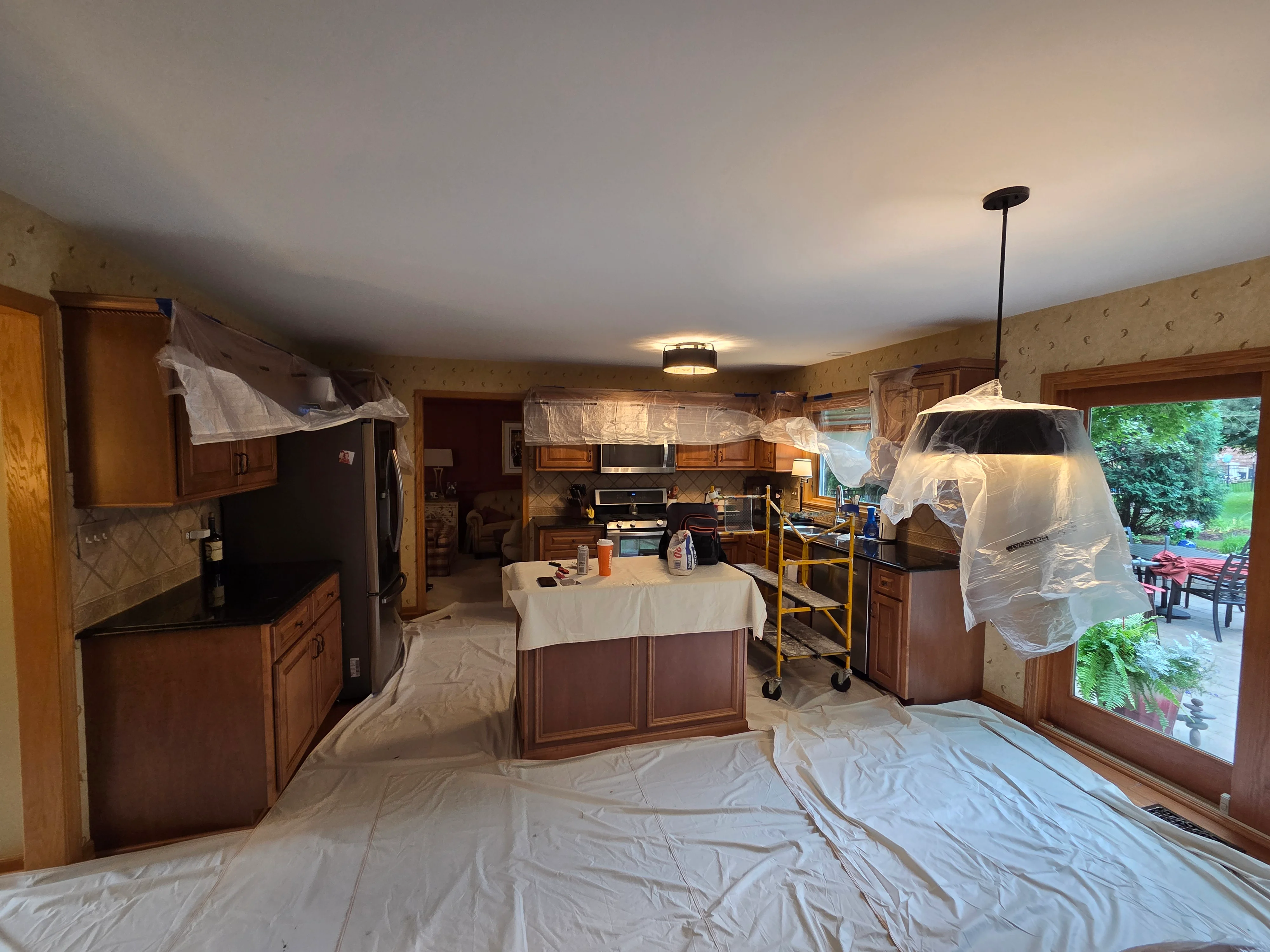 Kitchen interior with plastic sheeting covering cabinets and island, prepared for painting work