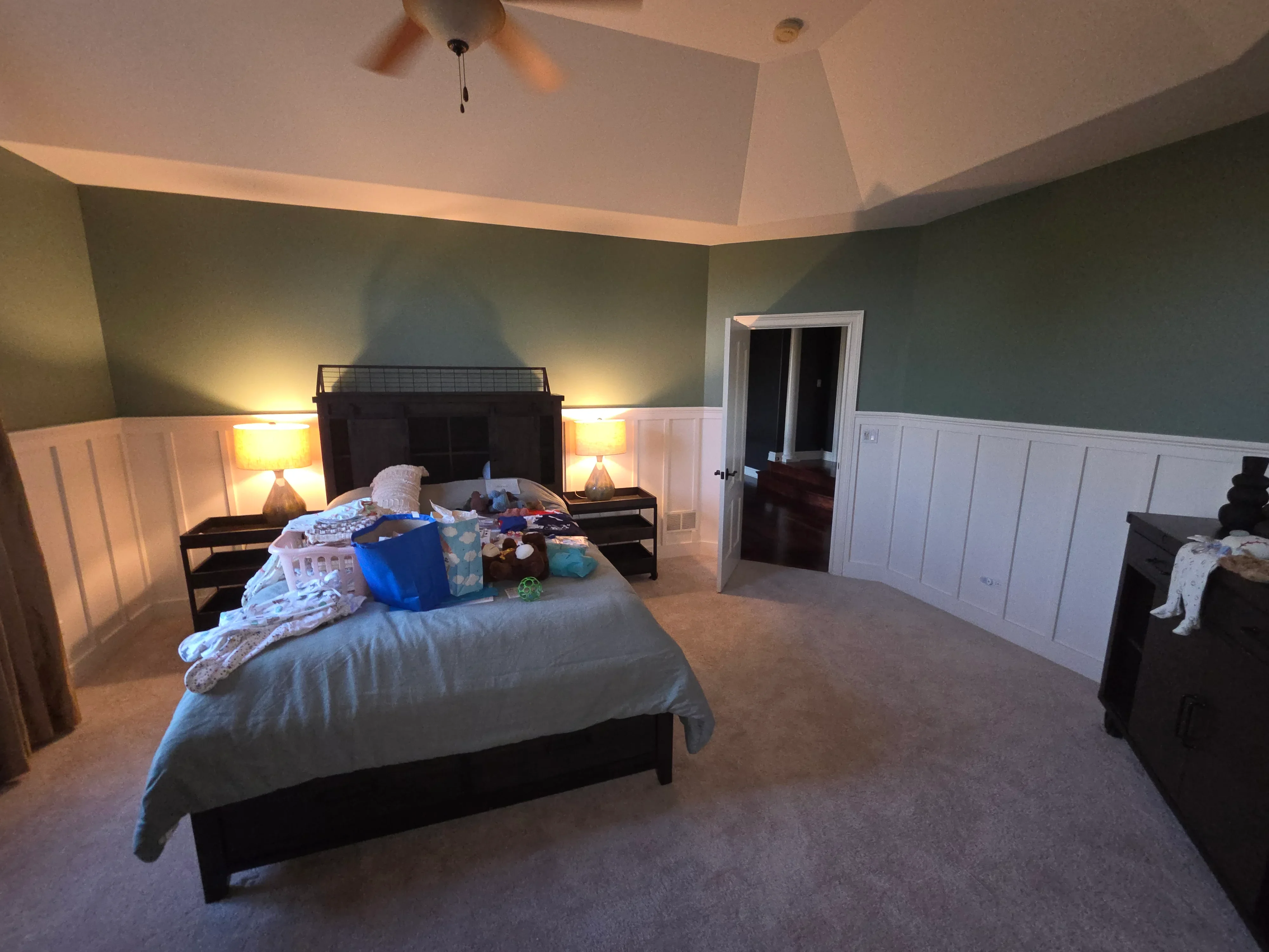 Master bedroom with sage green walls, white wainscoting, vaulted white ceiling, and recessed lighting